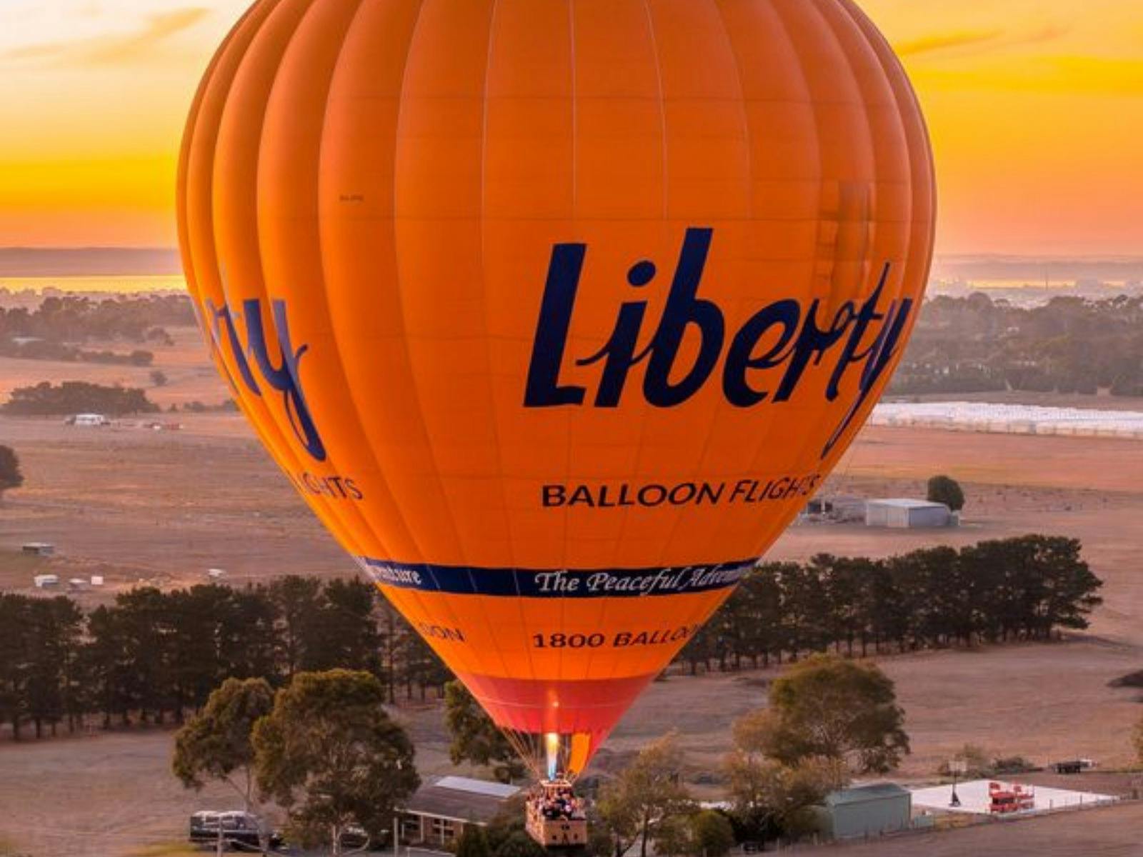 Hot air balloon adventure at sunrise, blending beautifully with the orange-hued sky