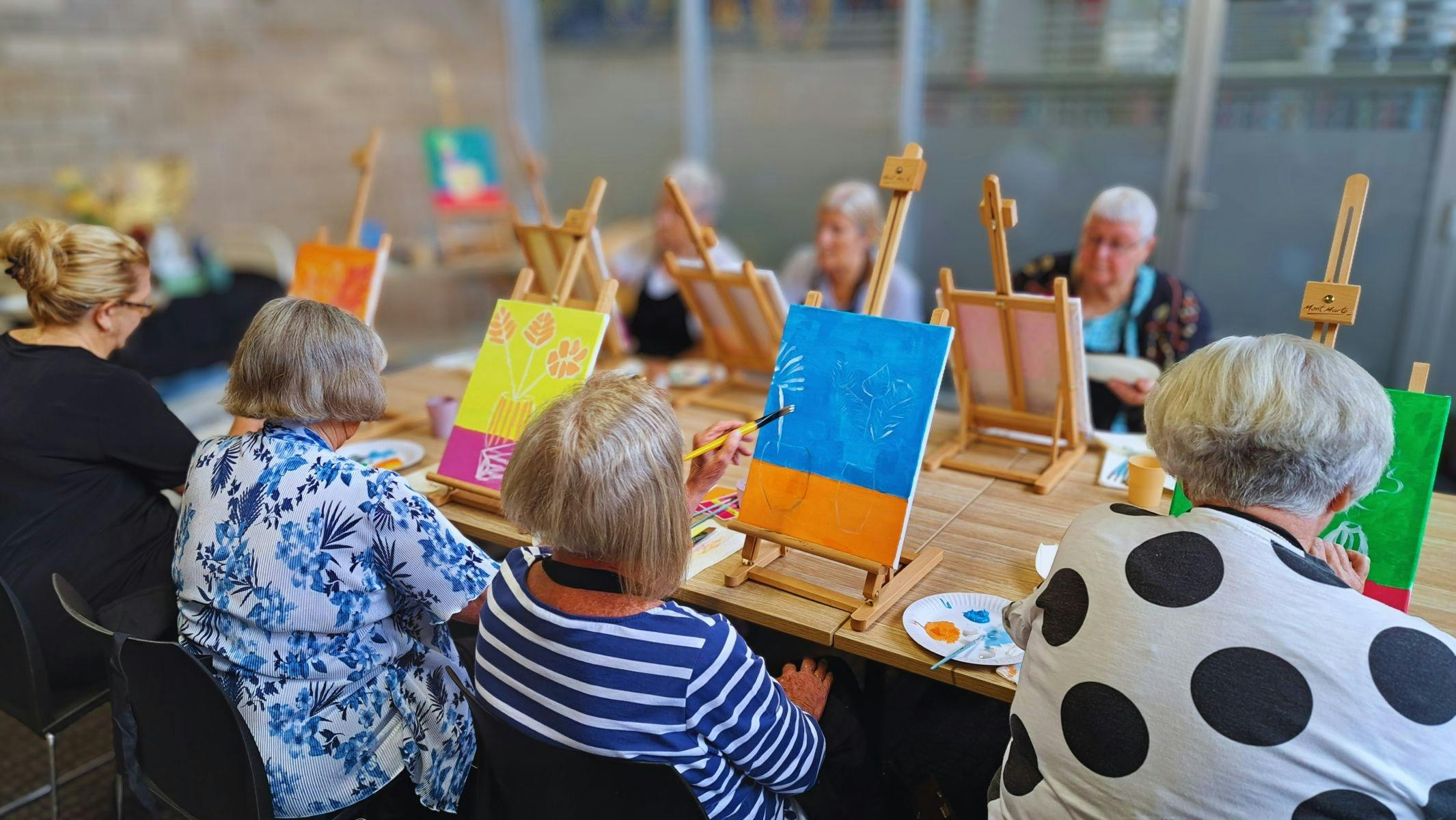 Group of senior women painting individual canvases