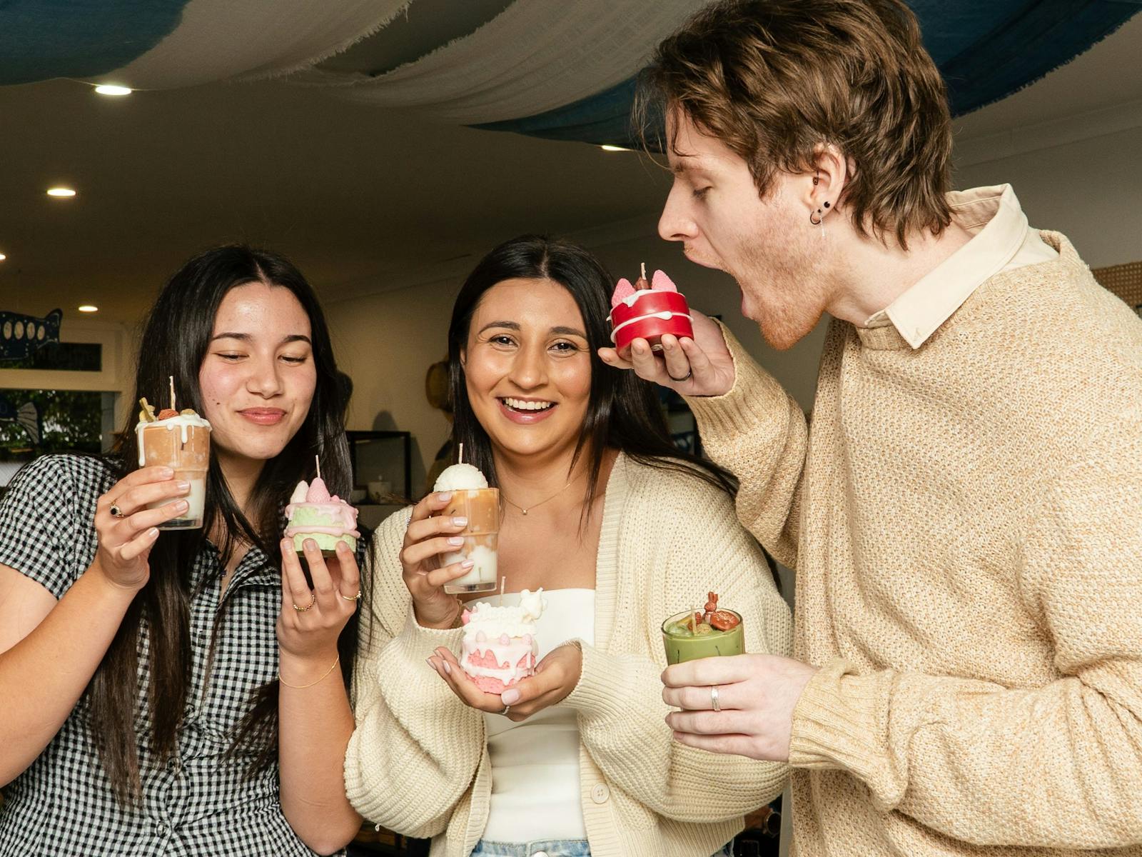 Three participants holding their handmade dessert candles and pretending to eat them