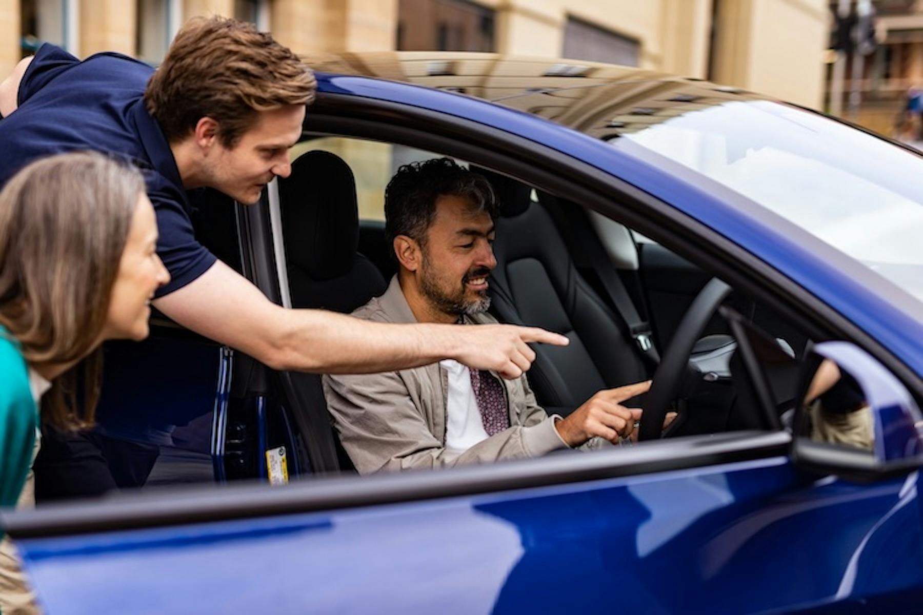 Car hire concierge showing a couple the features of a Tesla car