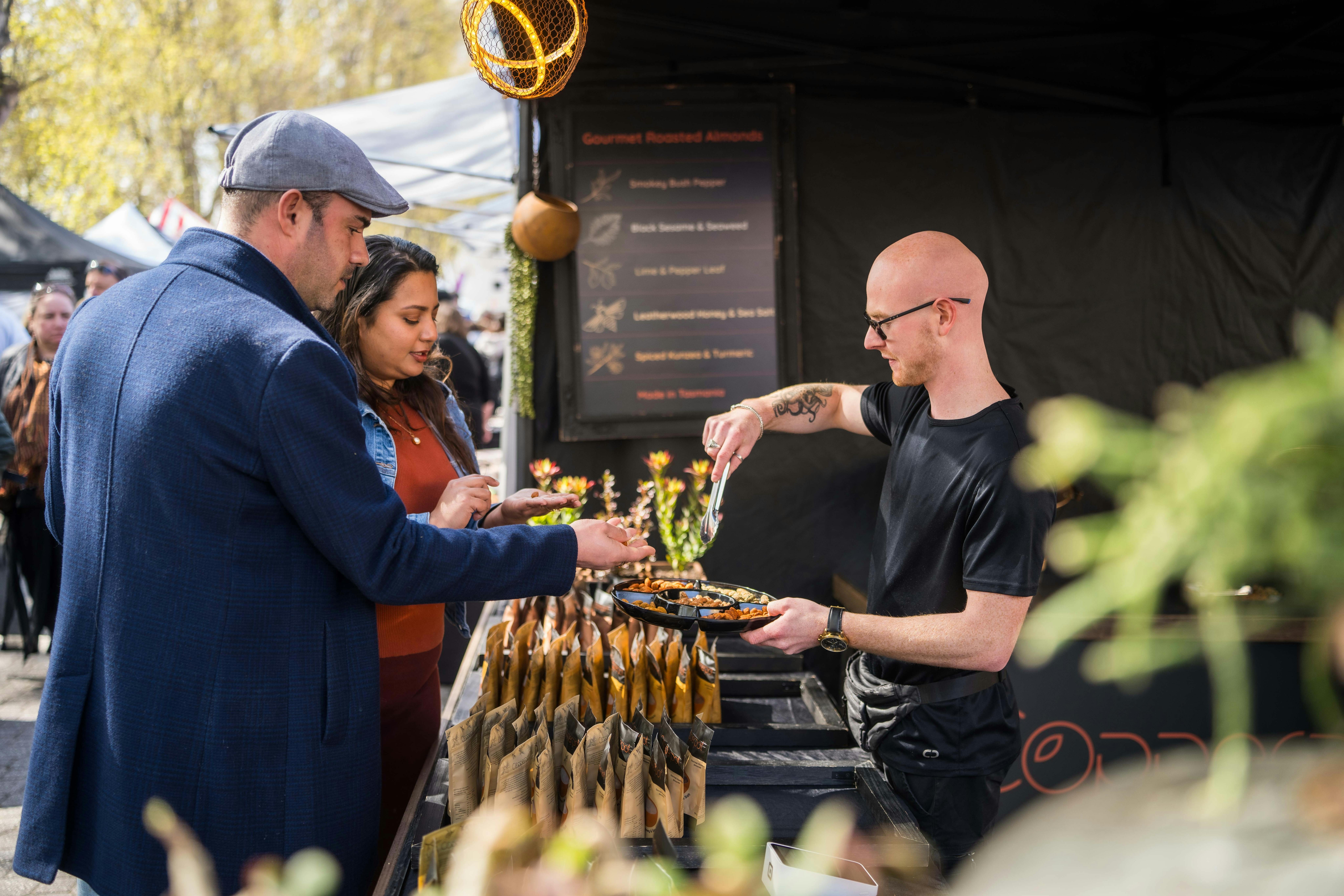 Two people tasting some food at a market stall