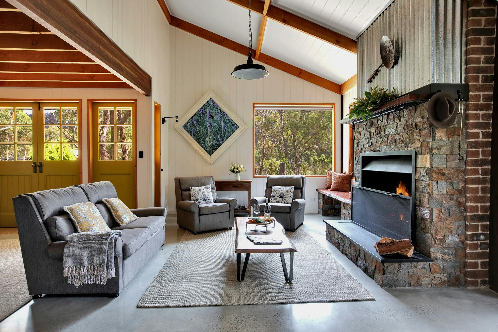 ラウンジと2脚のアームチェア、木製のコーヒーテーブル、大きな窓のあるリビングルーム