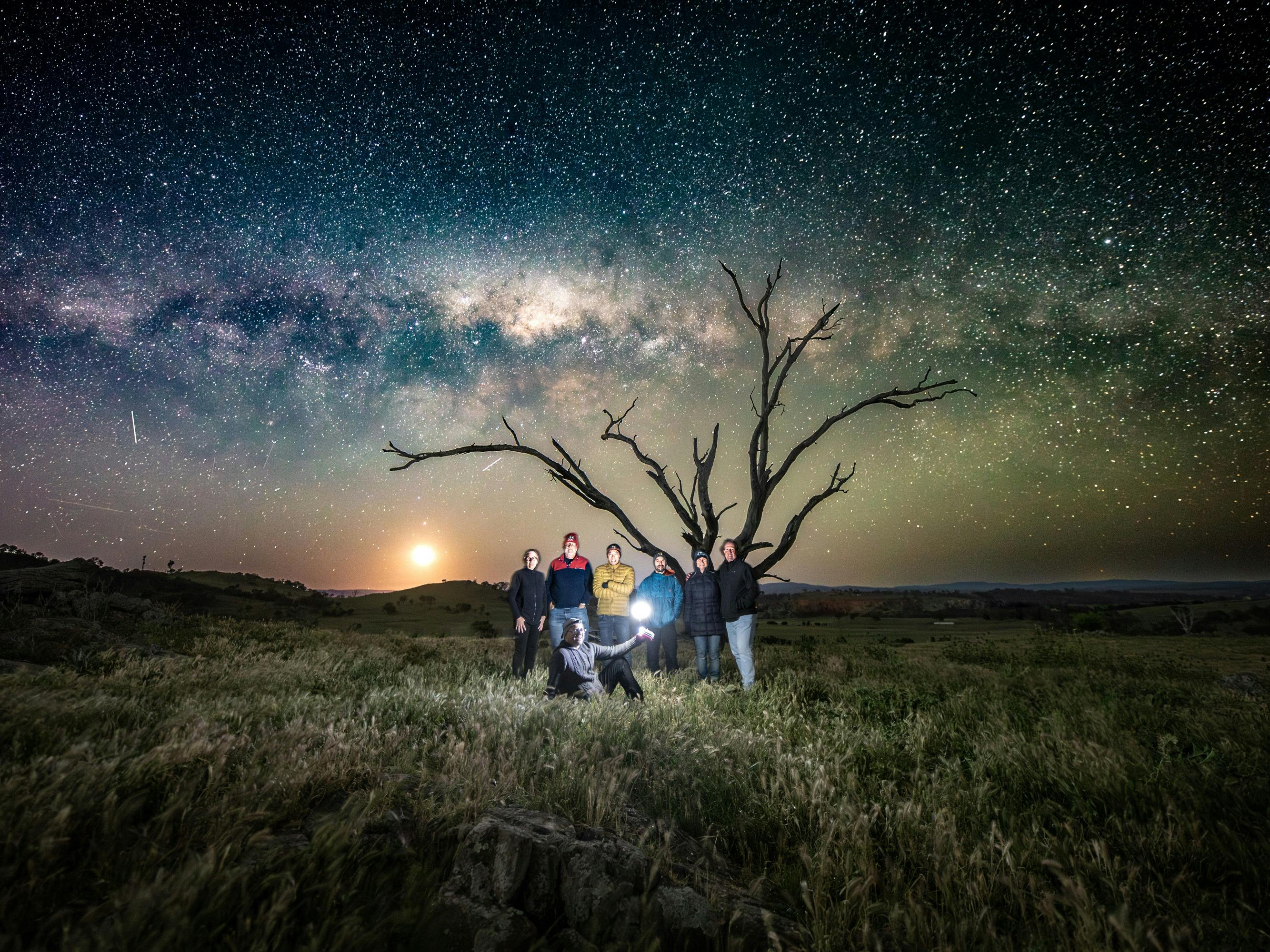 A moon and Milky Way portrait of a group of people
