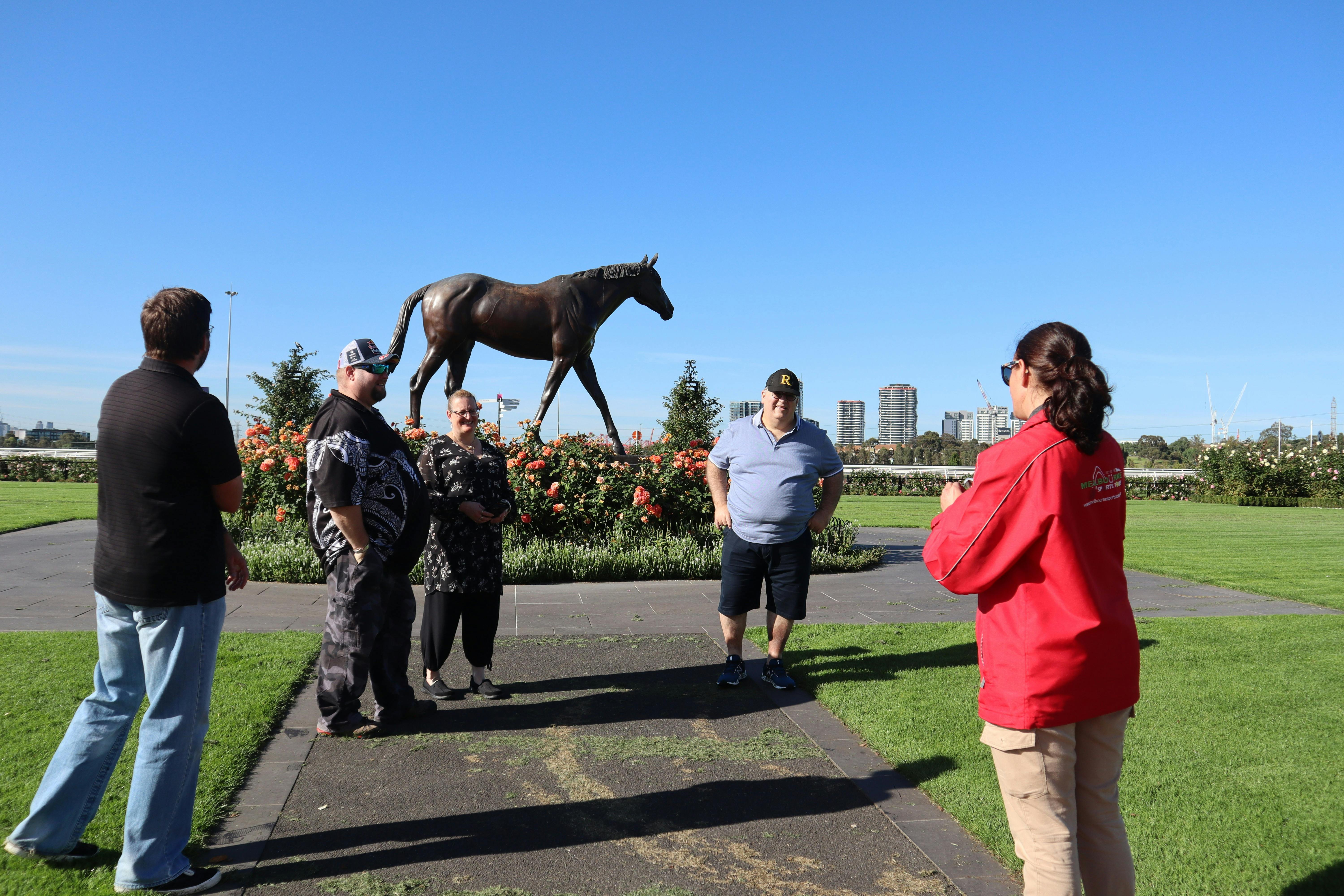 Tour host and guests standing in front of a statue of racehorse Makybe Diva