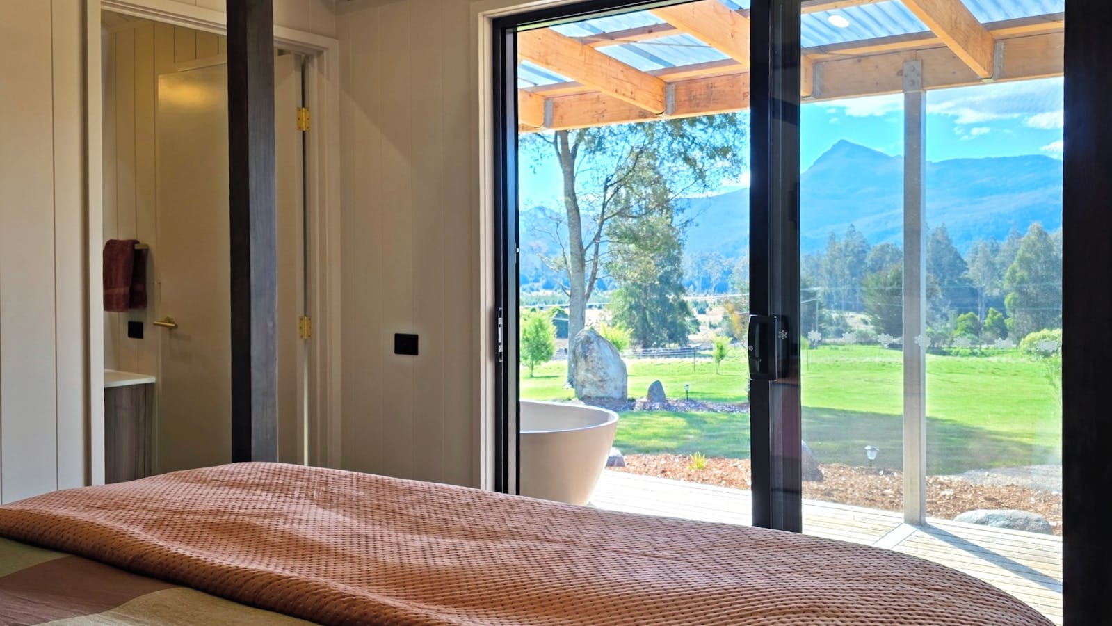 Views from the four-poster king bed across the garden to the forest and mountain peaks beyond