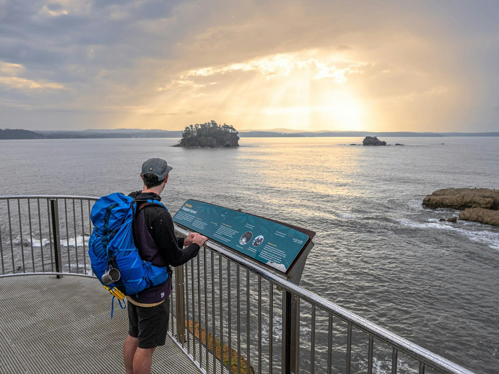man on a lookout platform with a view across an ocean bay and islands