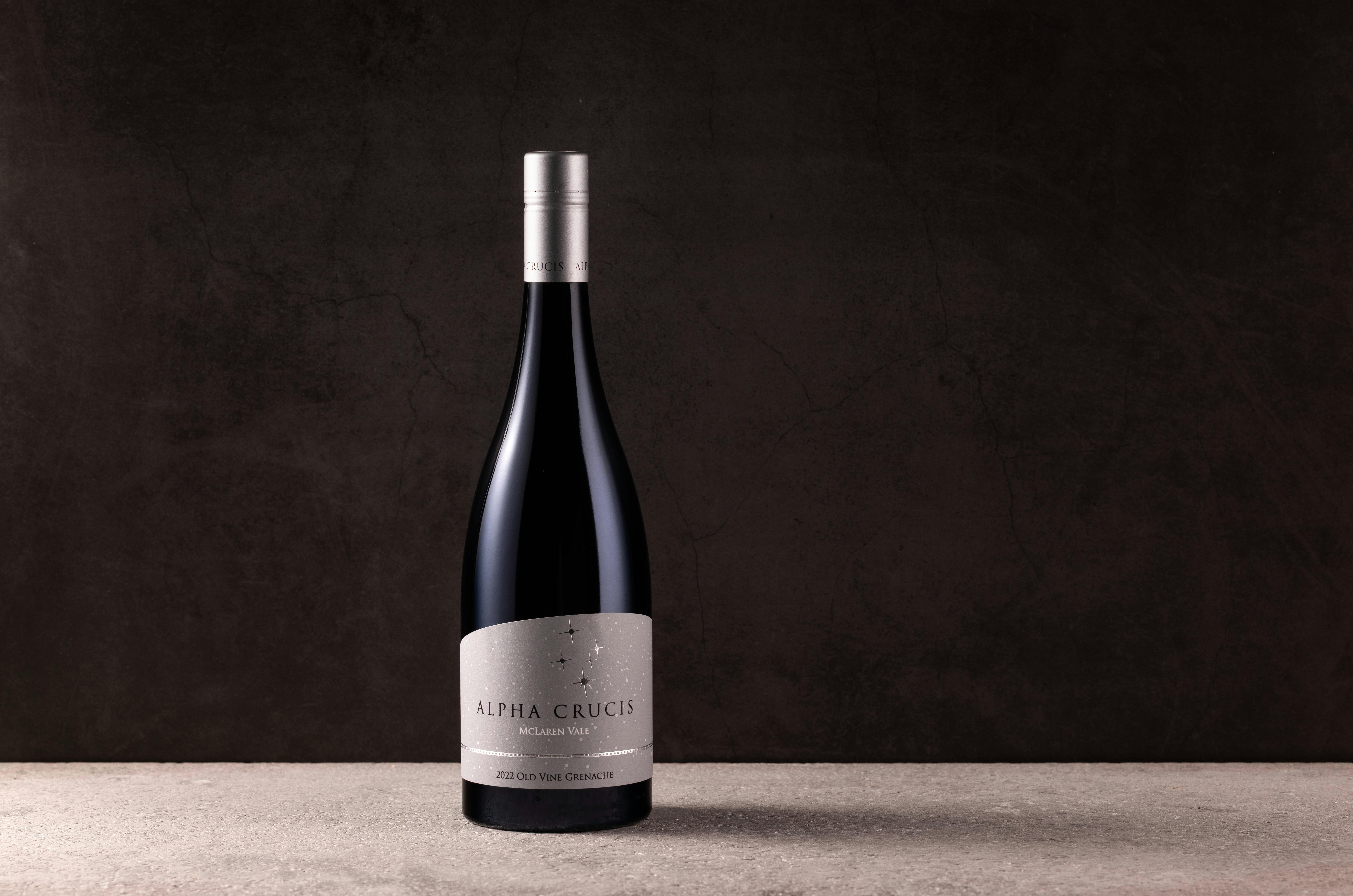 Wine bottle with gray label on gray floor with dark backdrop