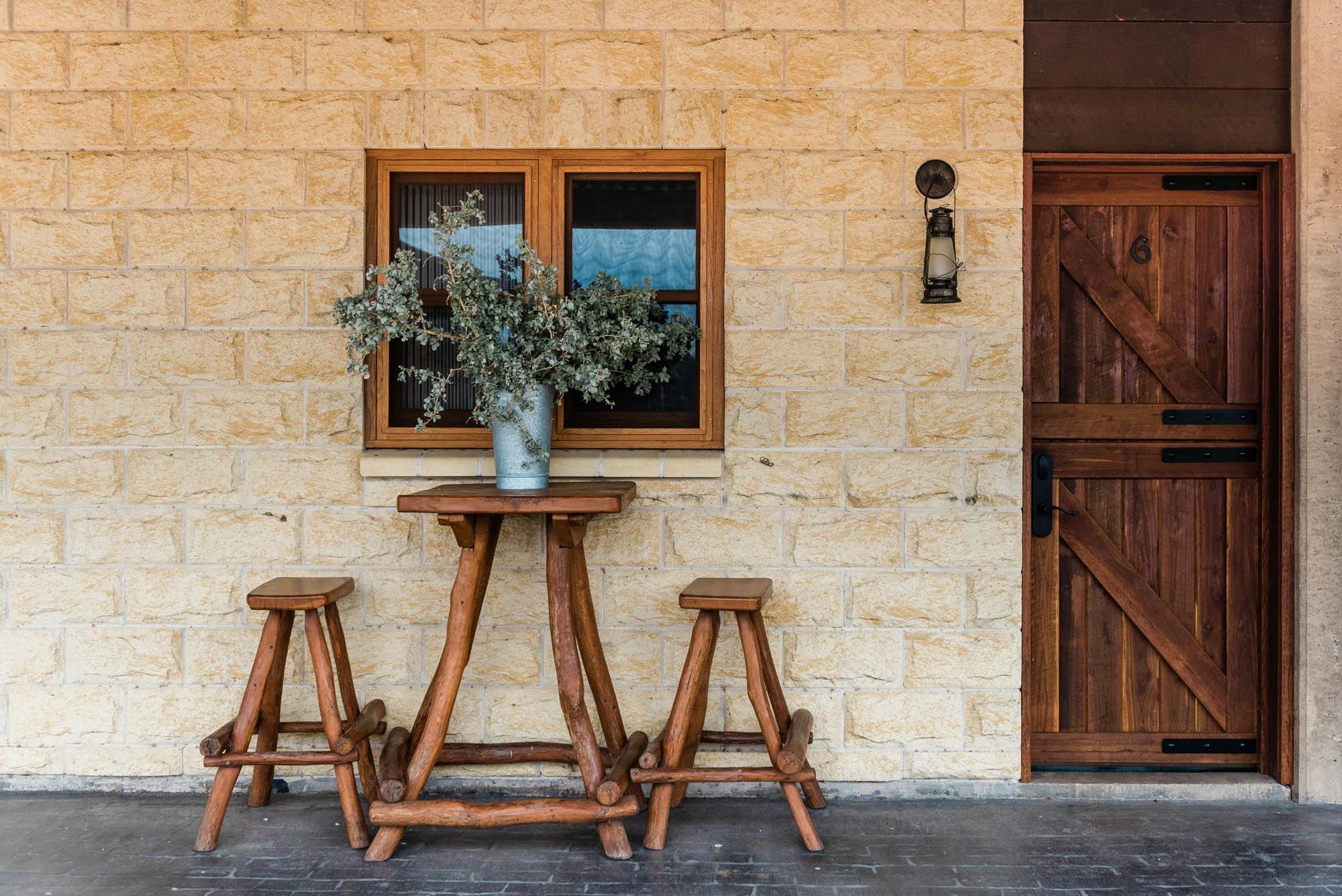 Wooden stools and table next to cream brick walled building