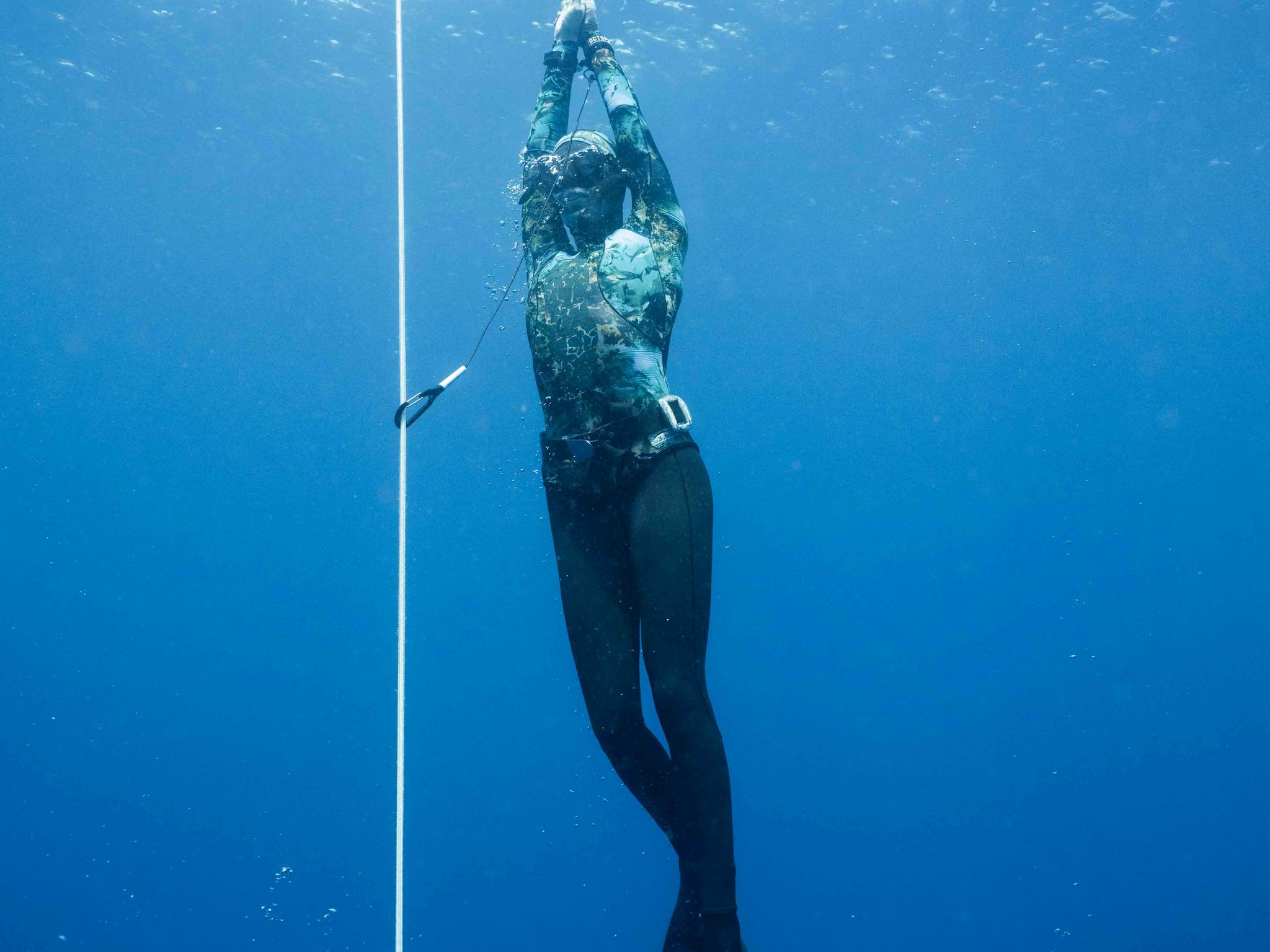 Freediver diving up along the line towards the safety buoy Freediver diving up along the line towards the safety buoy