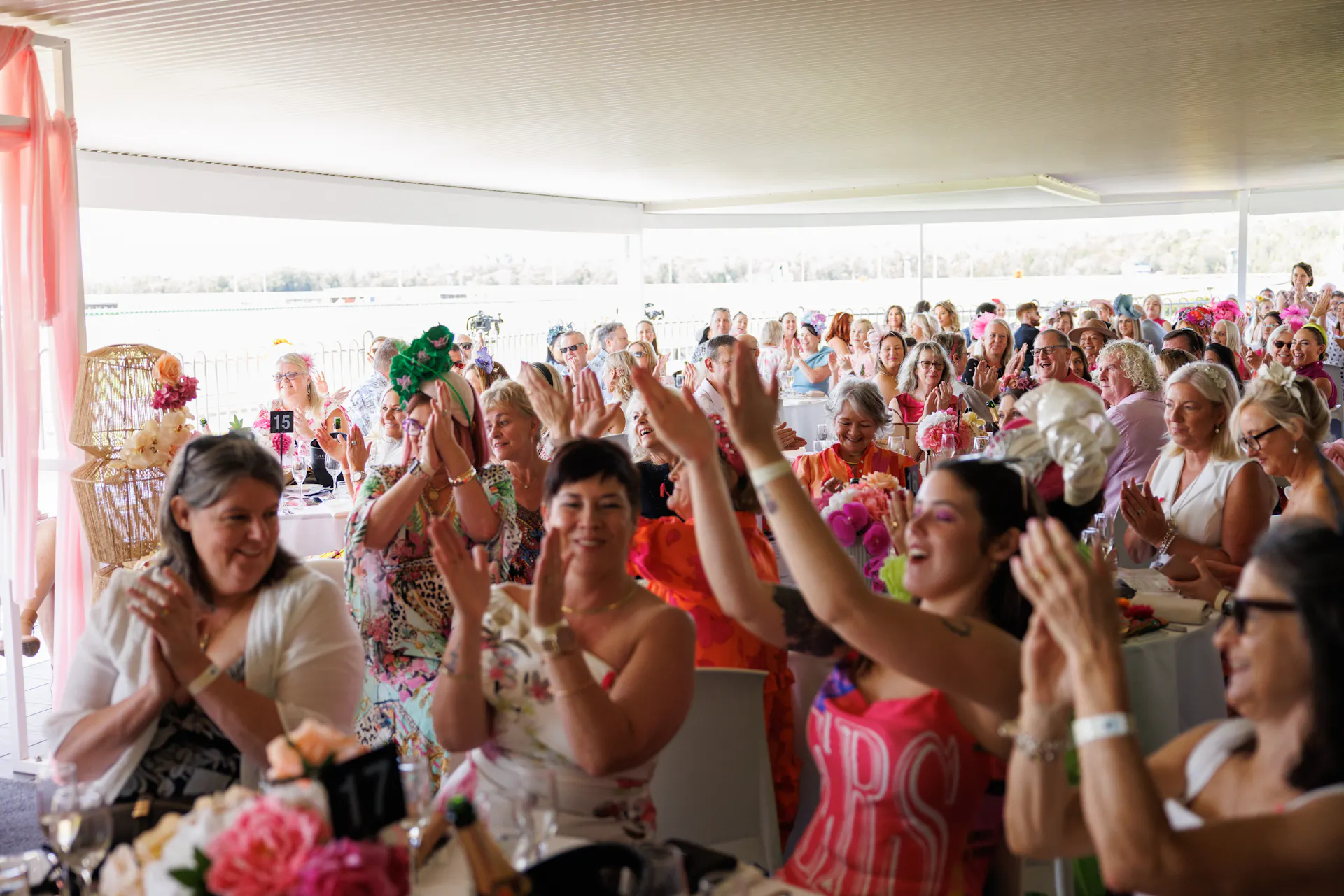 Crowd of people clapping and cheering in the Champagne Garden event dressed in pink