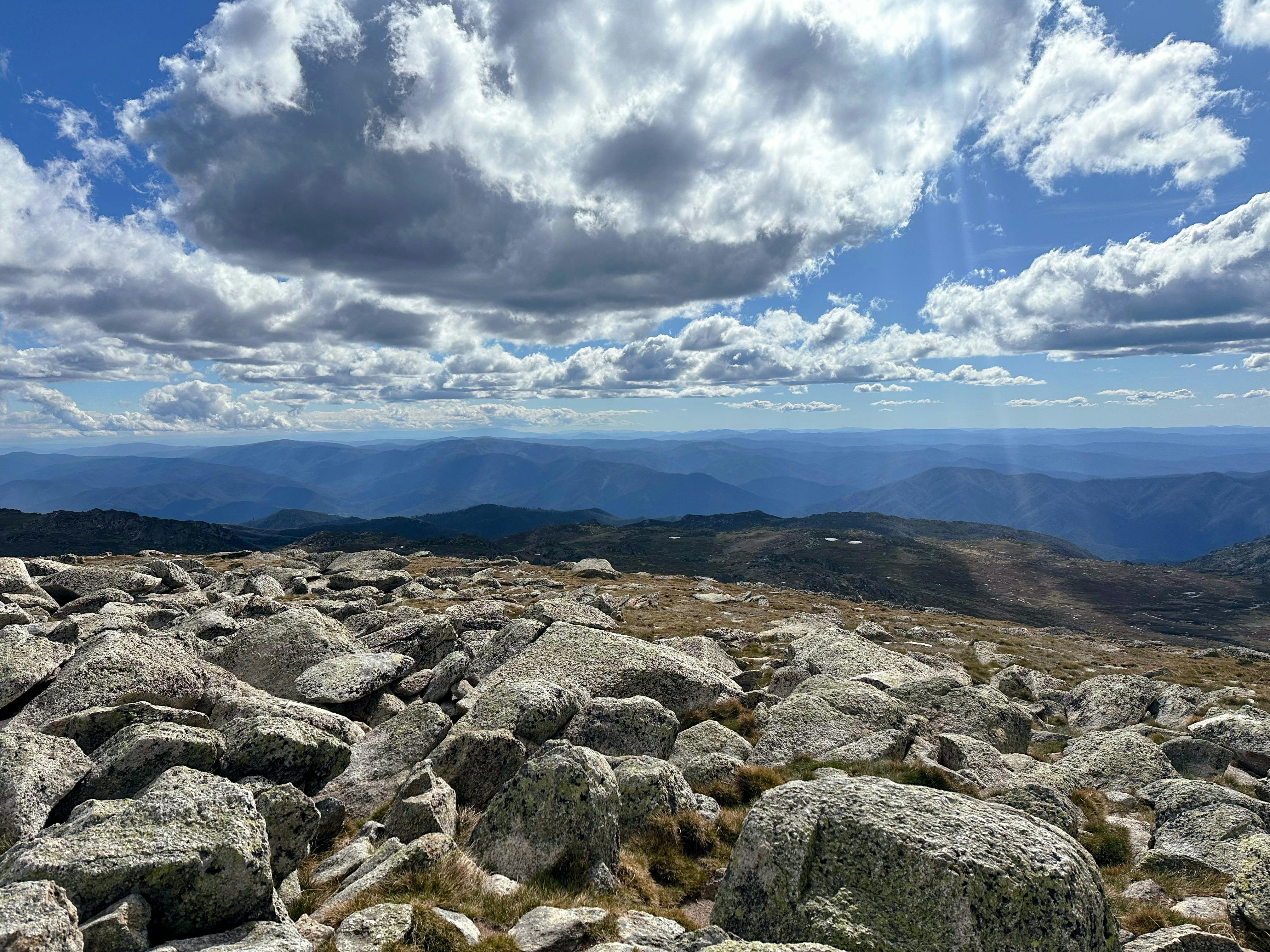 Views of the mountains with some rock in the foreground and heavy clouds above.
