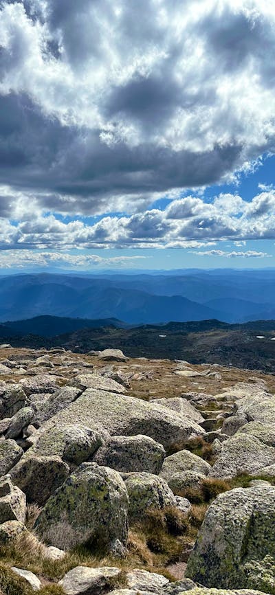 Views of the mountains with some rock in the foreground and heavy clouds above.