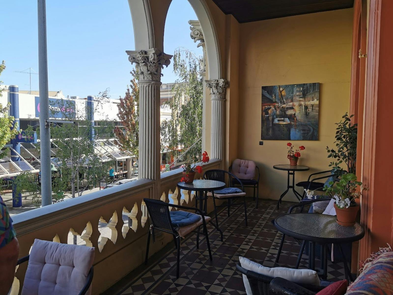 A heritage balcony overlooking Brisbane Street in Launceston, furnished with small café tables.