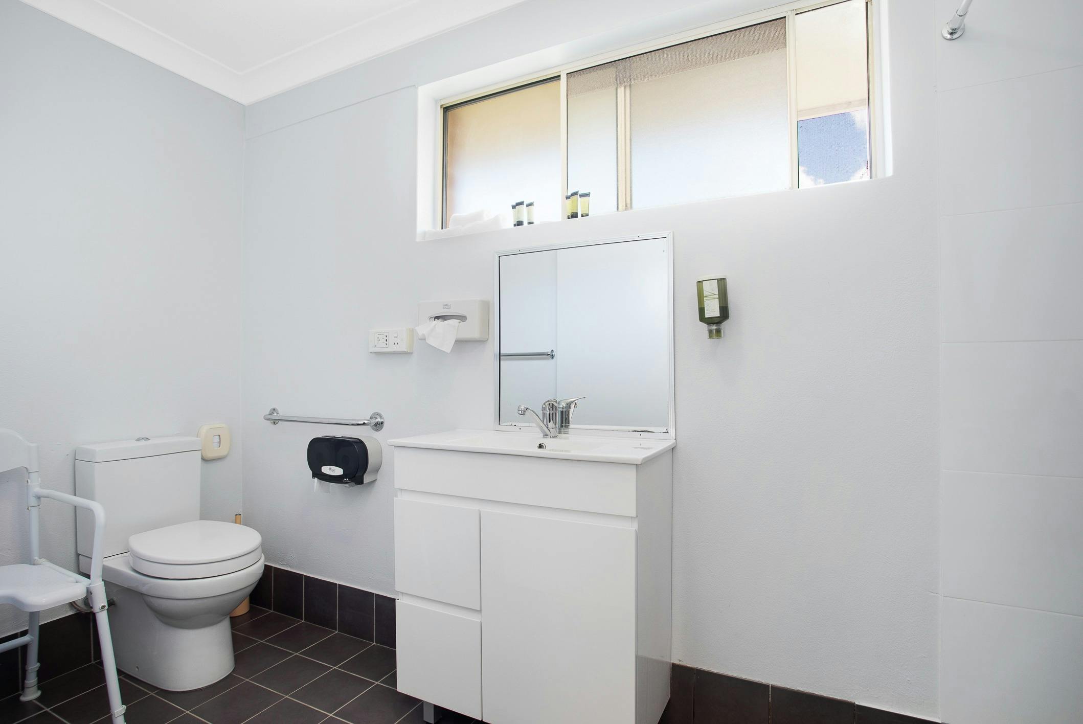 Accessible bathroom Raised toilet, hand rails, shower chair