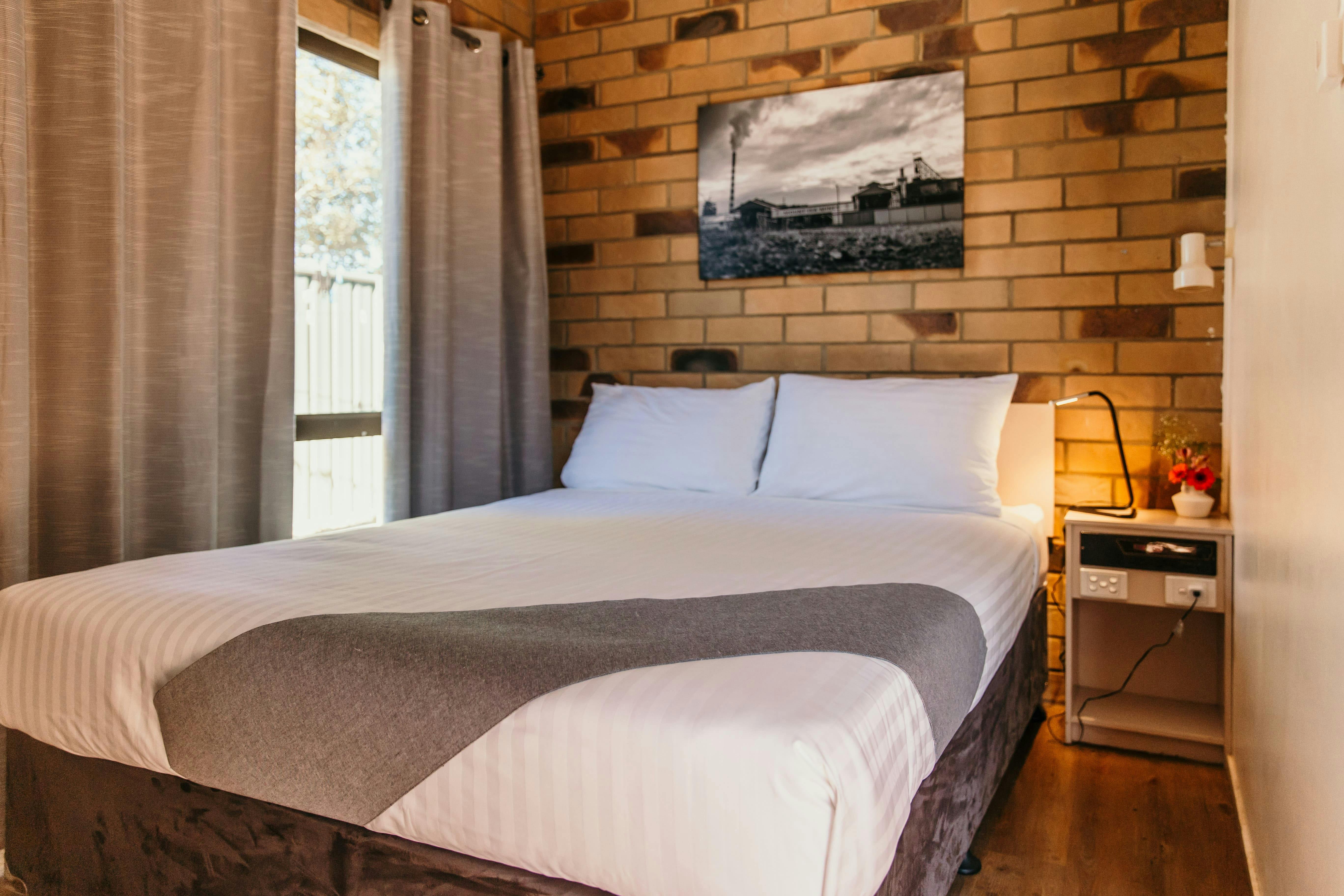 Queen bed with a lamp on the side table.