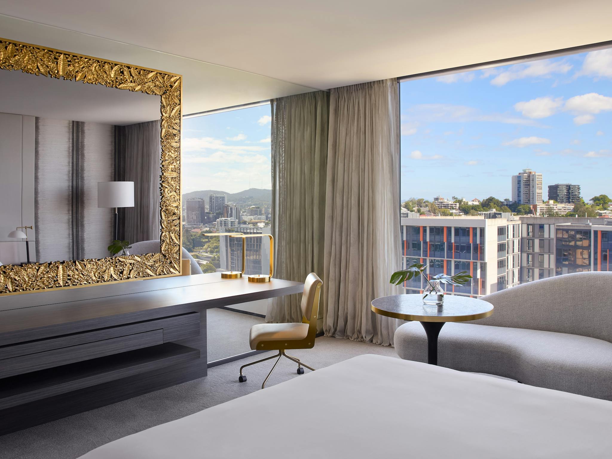 Luxury hotel suite with gold-framed mirror and floor-to-ceiling windows overlooking Brisbane Luxury hotel suite with gold-framed mirror and floor-to-ceiling windows overlooking Brisbane