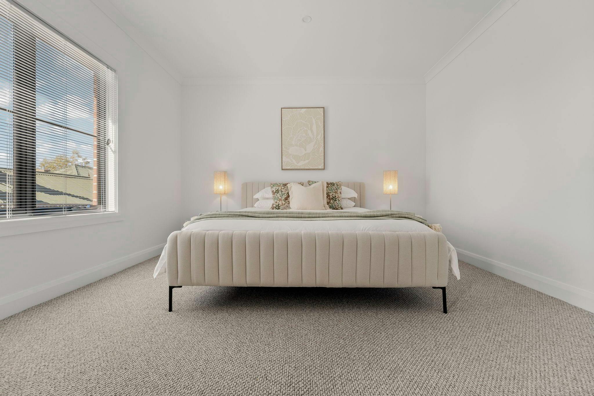 King bed with white linen, floral pillows and a green throw