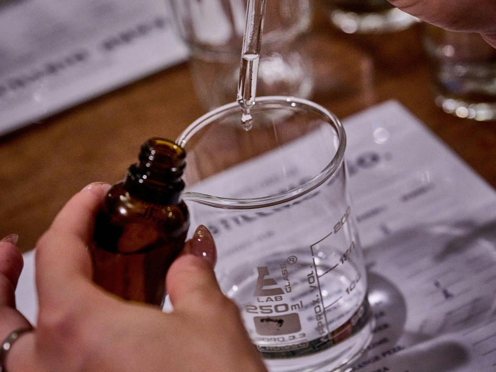 A hand carefully drops distillates into a beaker