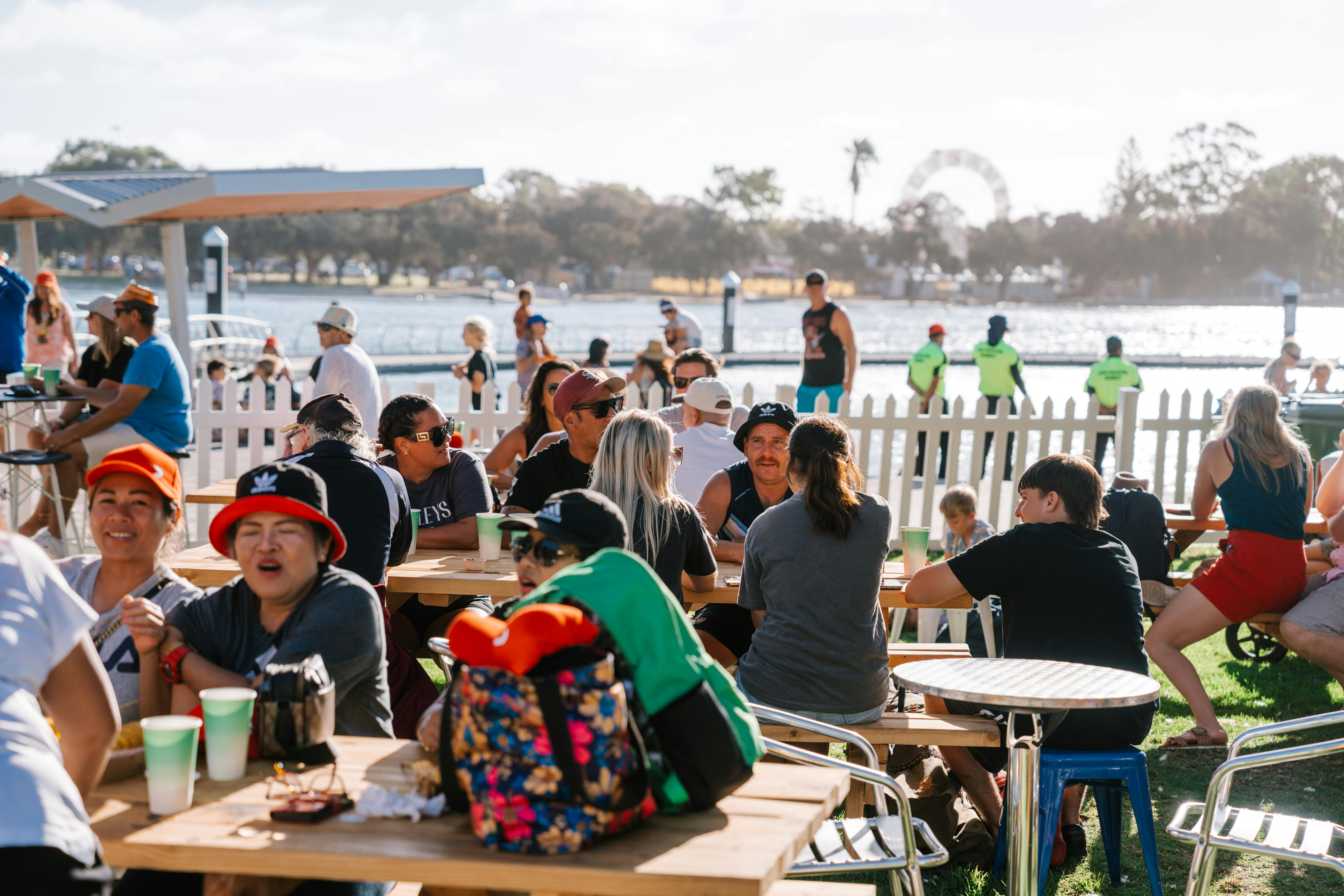 Crowd sitting down enjoying food with water in the background
