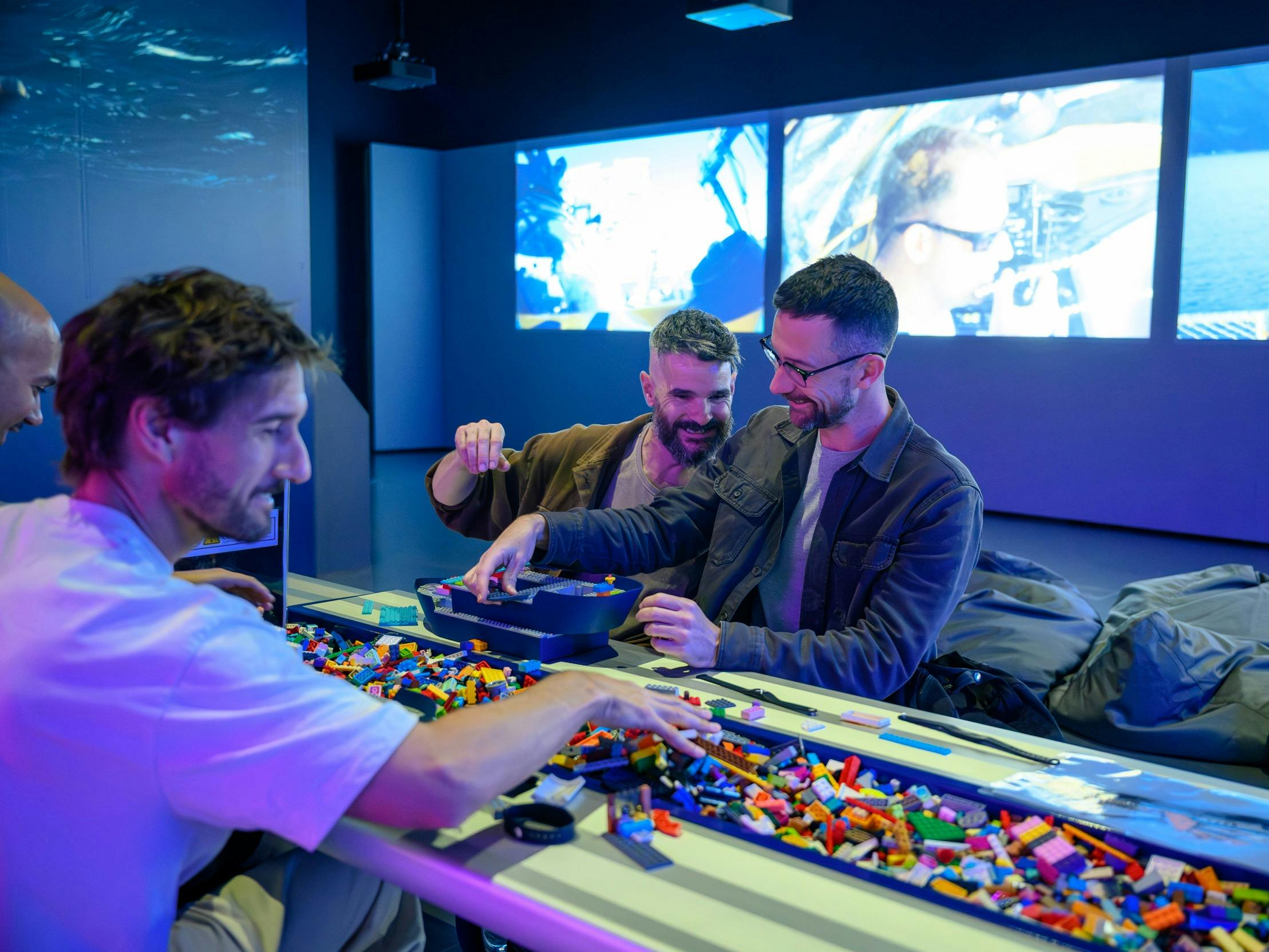 A group of men playing with lego inside a Museum exhibition