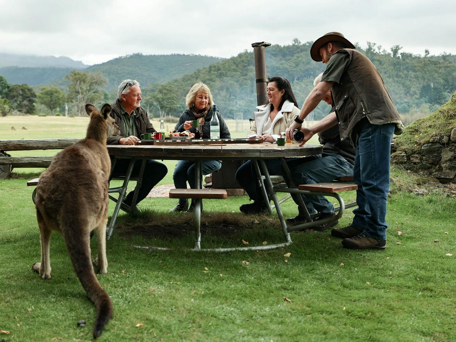 outside dinning with kangaroo looking on