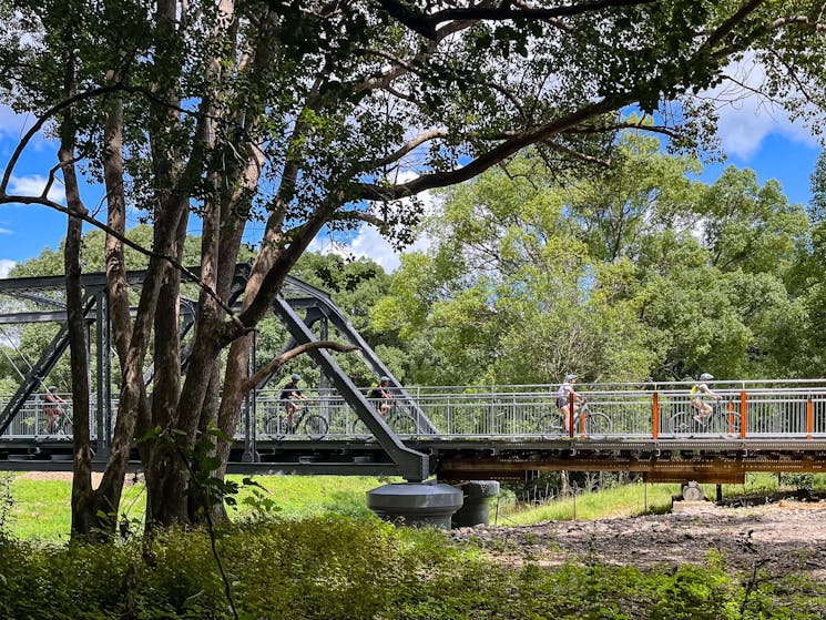 Side view of Dunbible Bridge on the Northern Rivers Rail Trail with group of E Bike riders crossing.