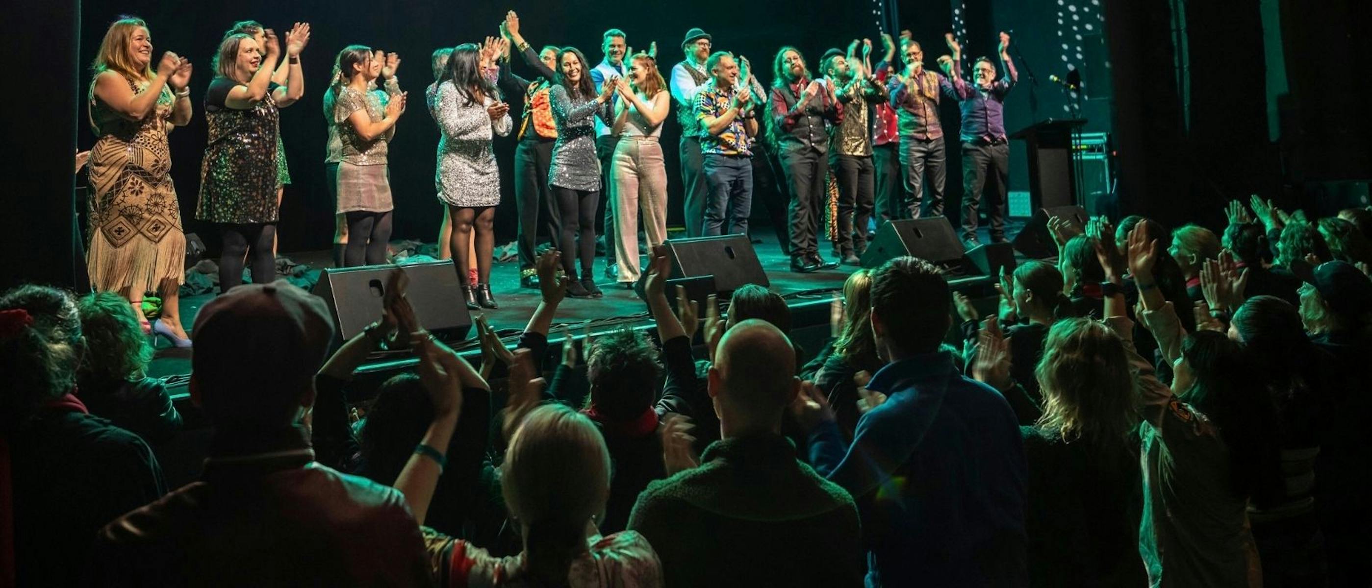 A group of people on stage applauding, in front of an audience