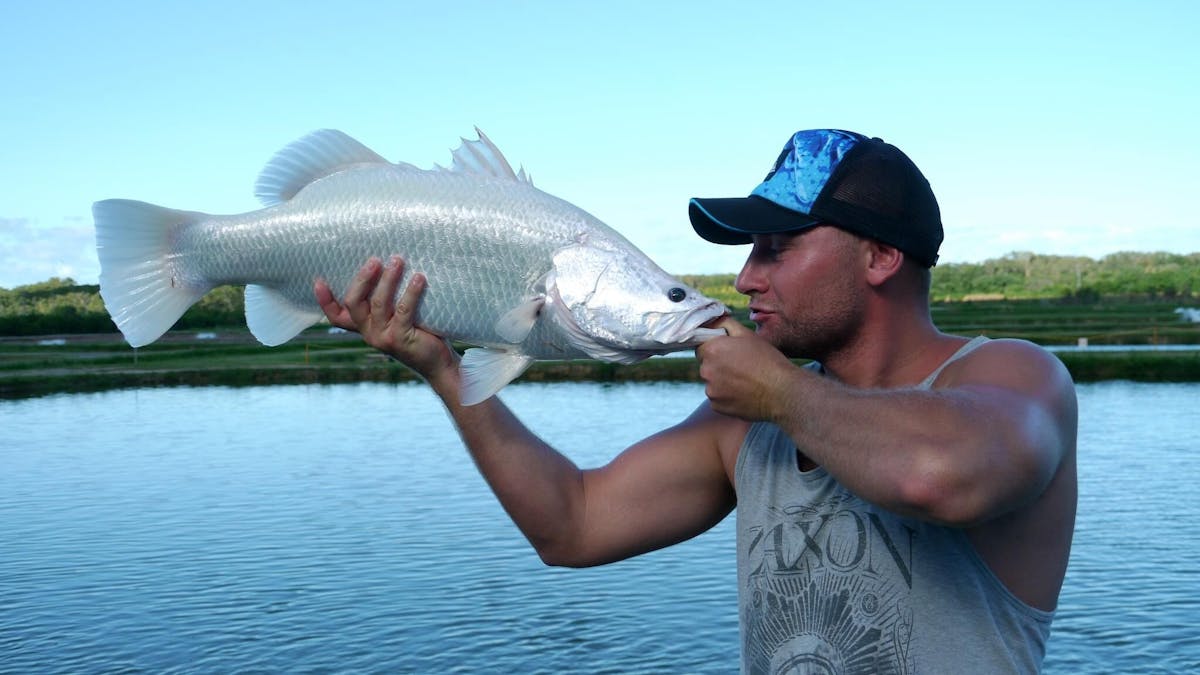 Man holding up an albino barramundi