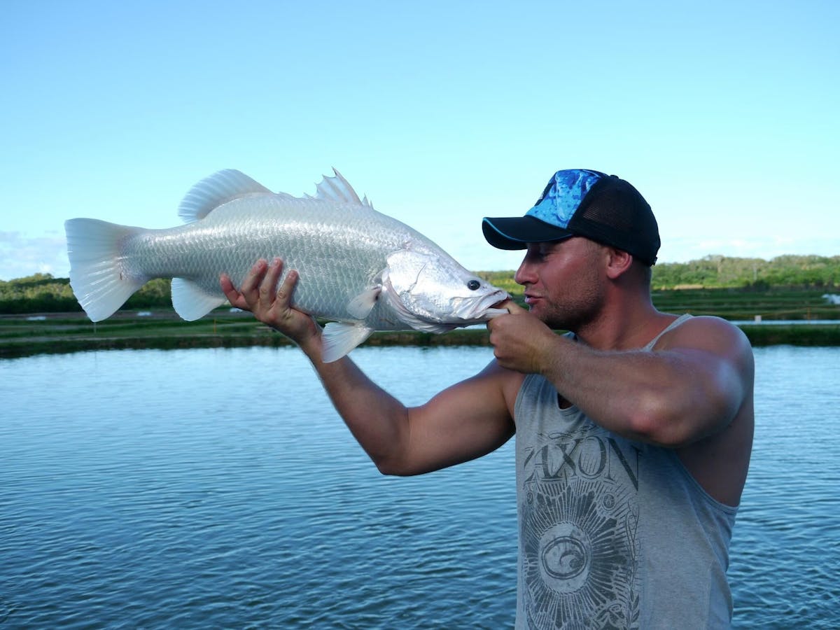 Man holding up an albino barramundi