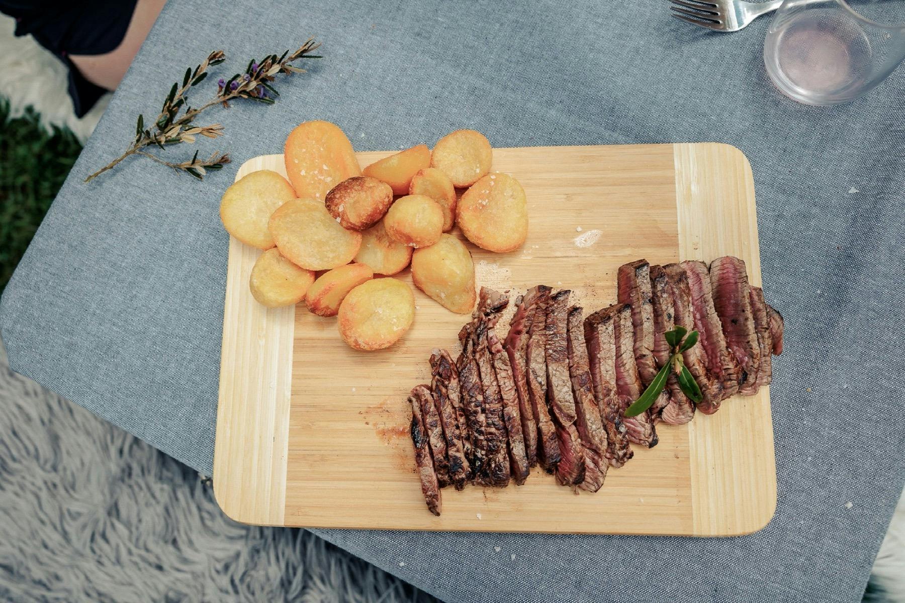 Wooden board with meat and potatoes