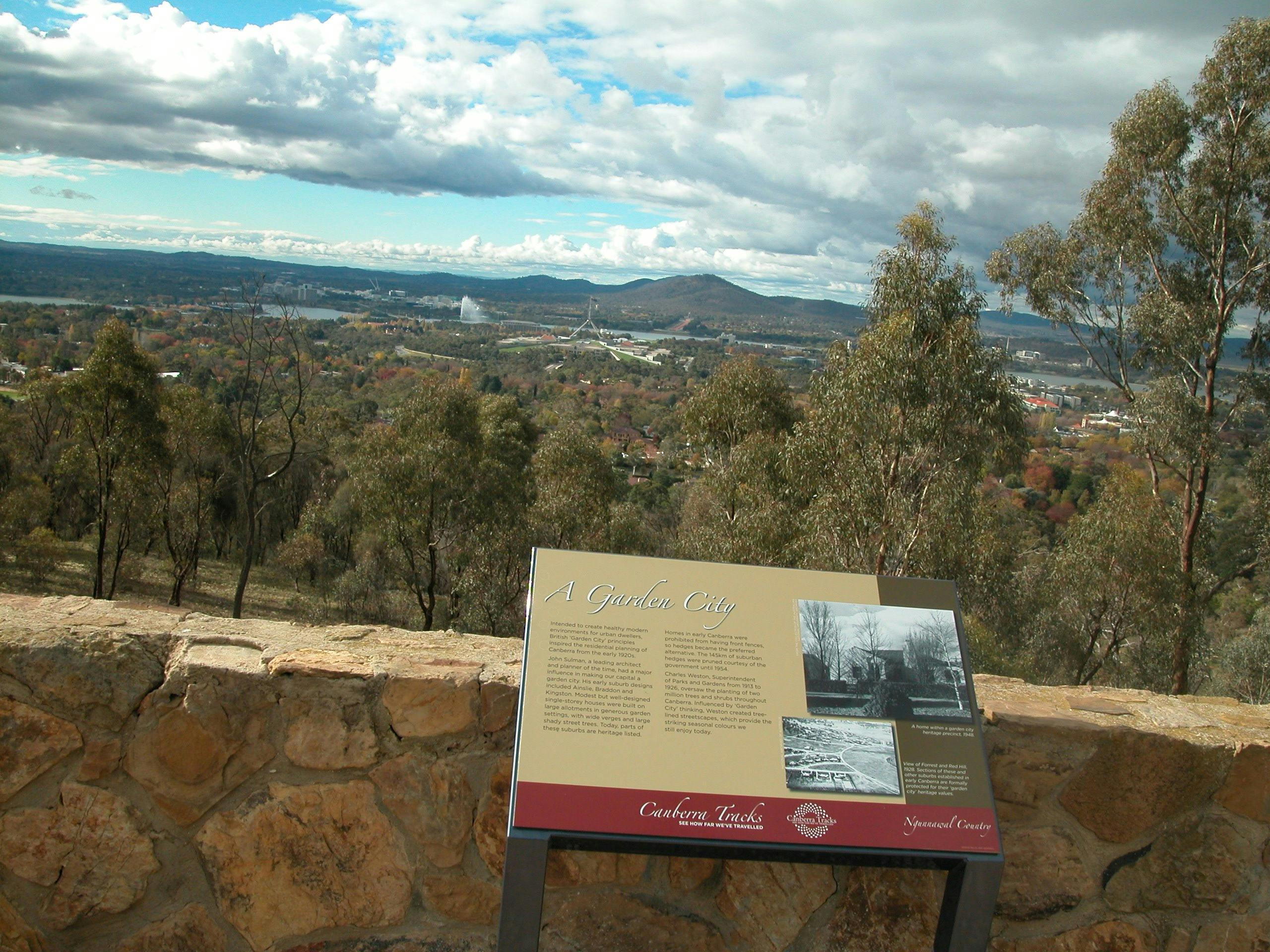 Information panel against stone wall with view of trees and hills