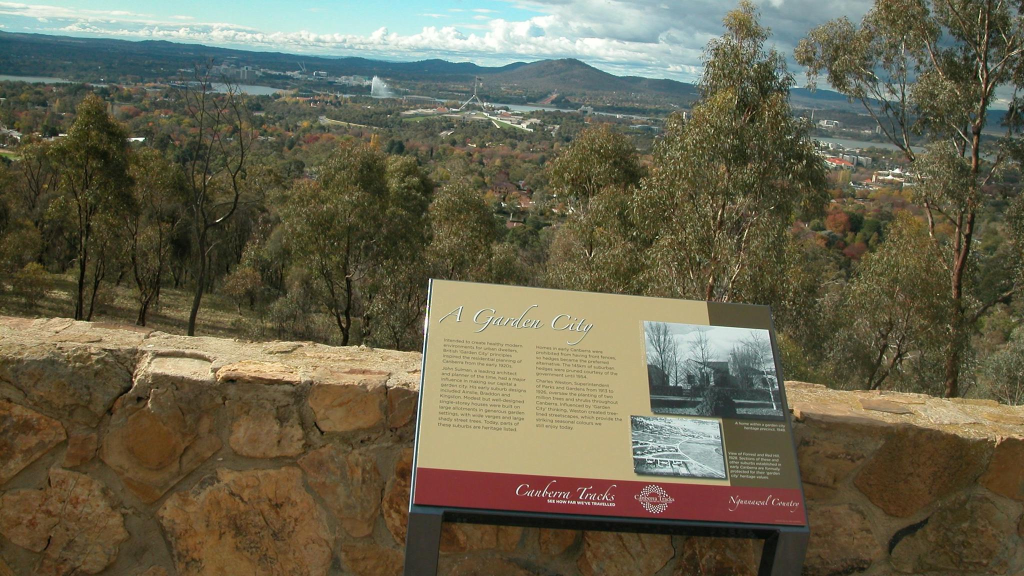 Information panel against stone wall with view of trees and hills