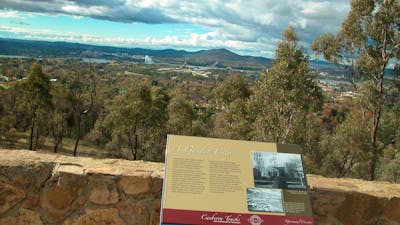 Information panel against stone wall with view of trees and hills