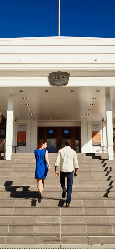 Two people walk up the steps of Old Parliament House