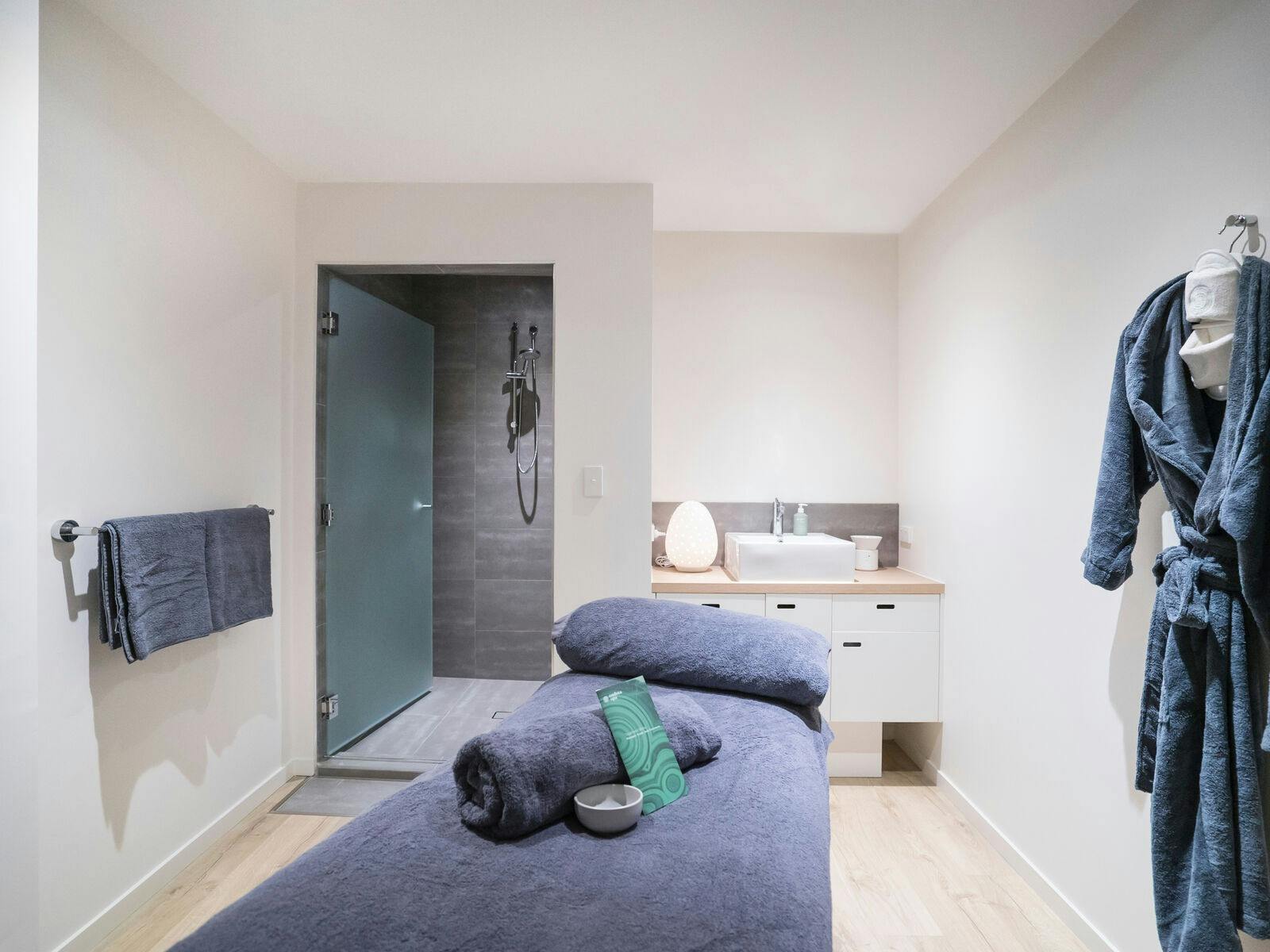 Charcoal spa bed in treatment room with shower and robe Charcoal spa bed in treatment room with shower and robe
