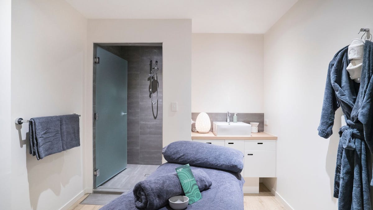 Charcoal spa bed in treatment room with shower and robe