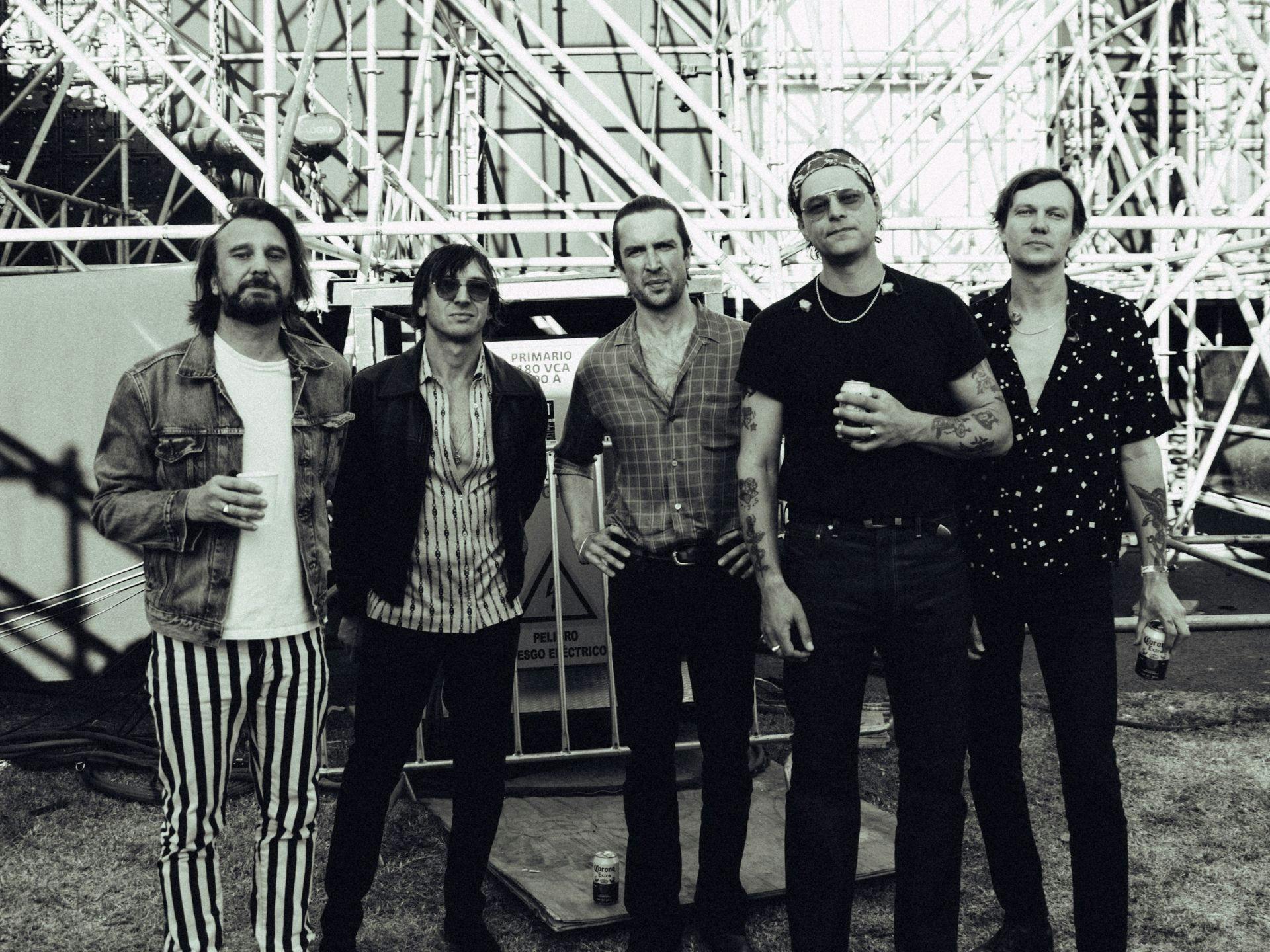 The band JET standing in front of a roller coaster