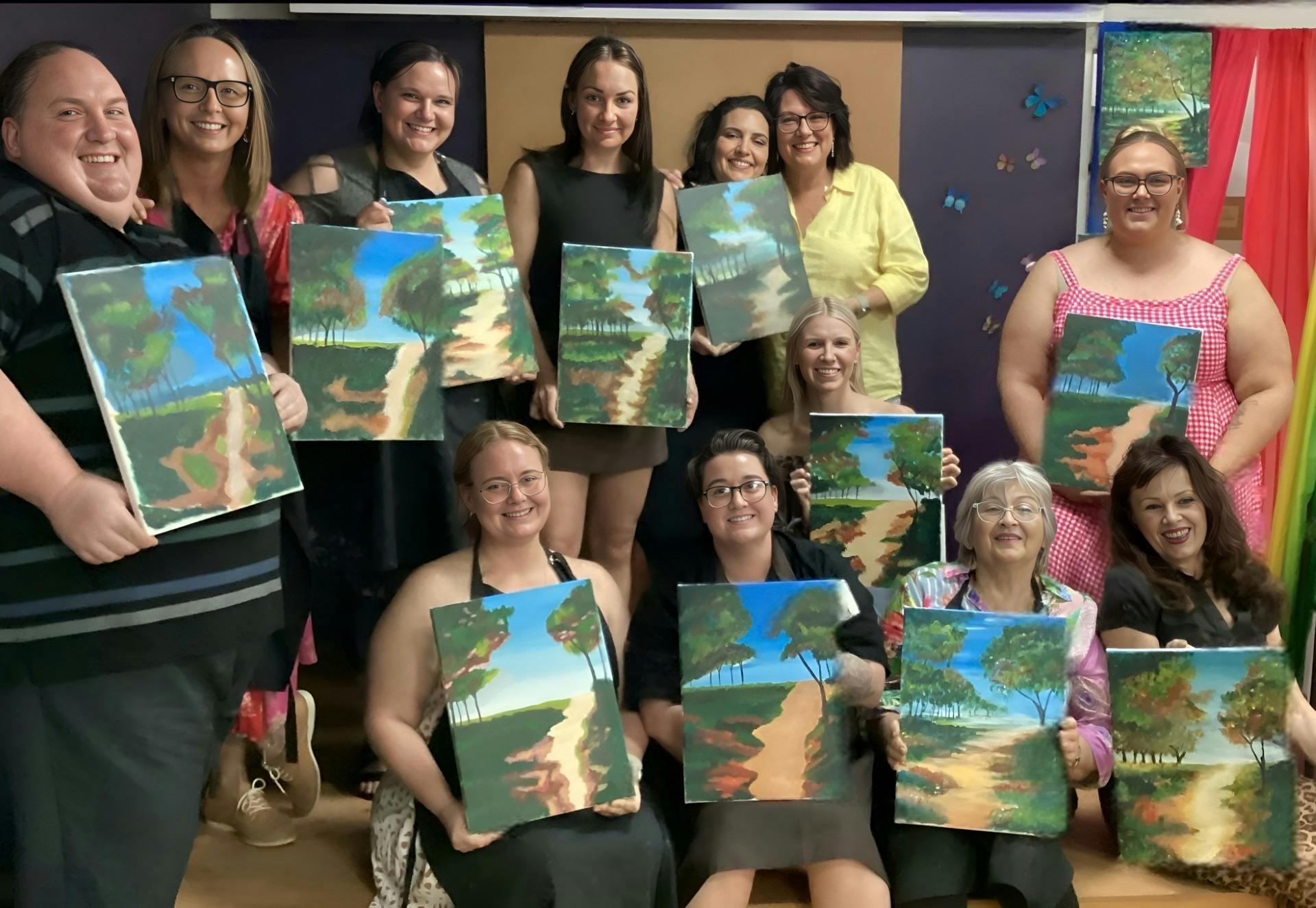 Artists proudly showing off their artwork of a beautiful beach scene.
