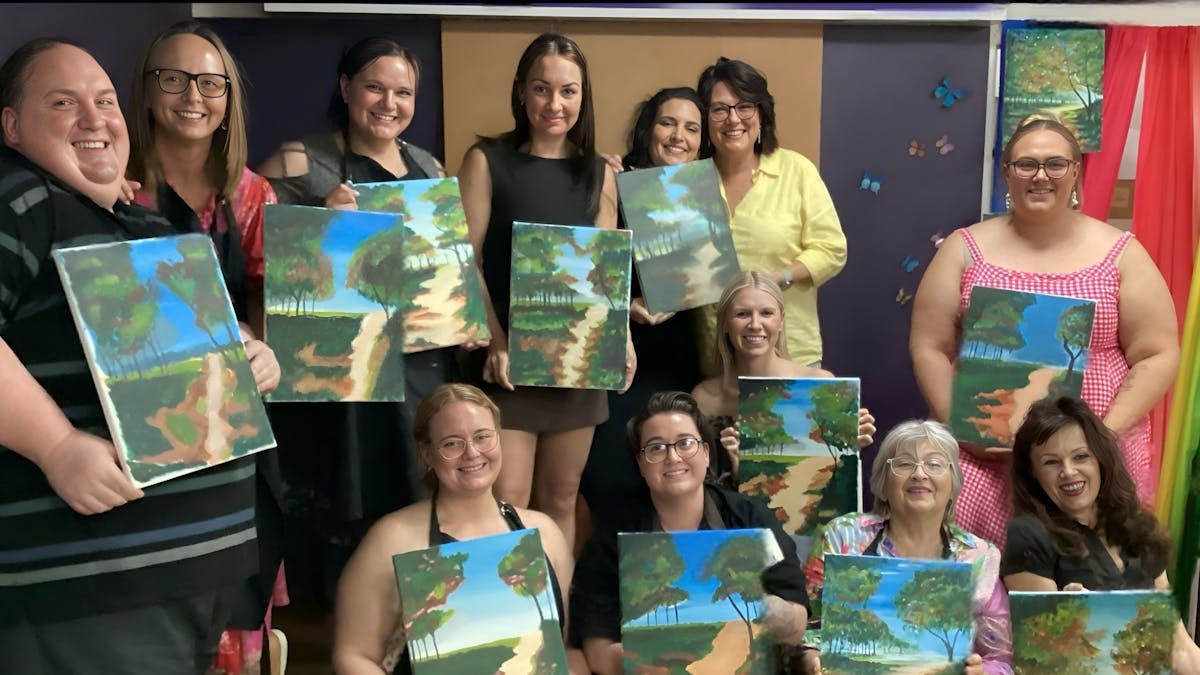 Artists proudly showing off their artwork of a beautiful beach scene.