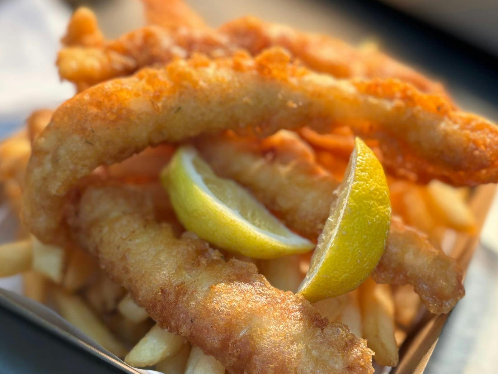 A close up photo of a serve of battered fish and chips.
