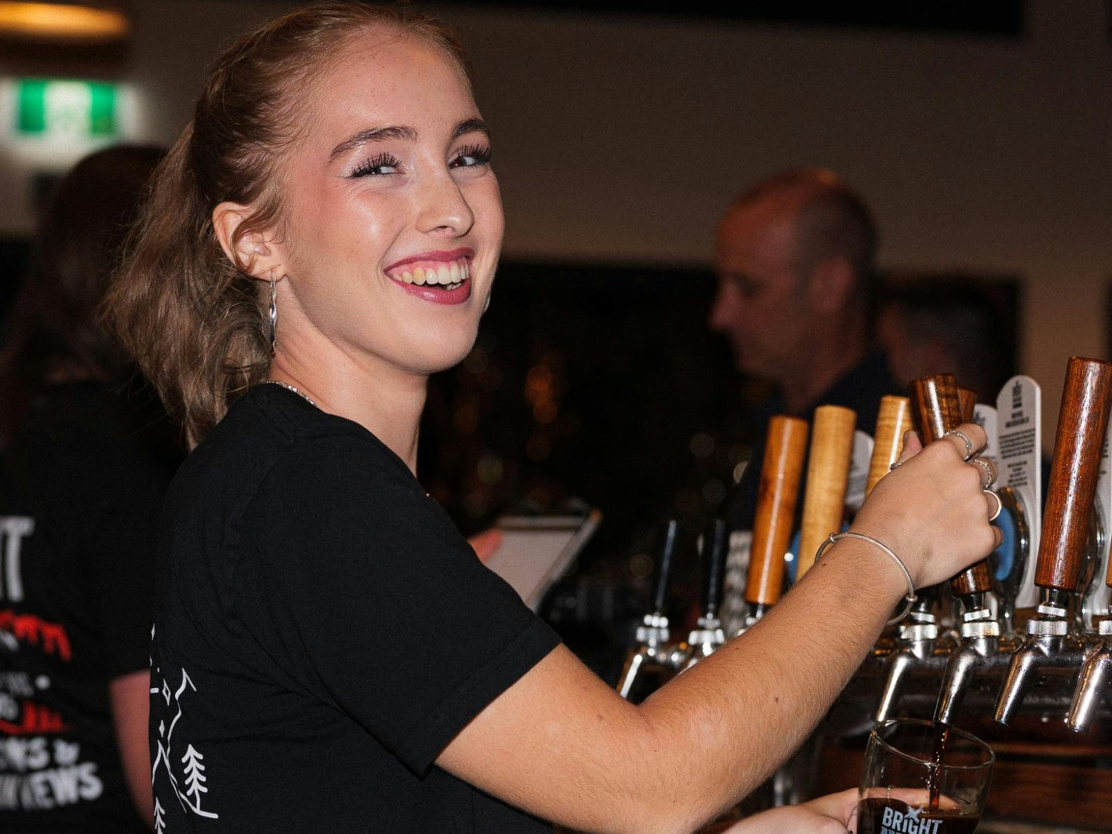 A female Bright Brewery bartender pouring a beer