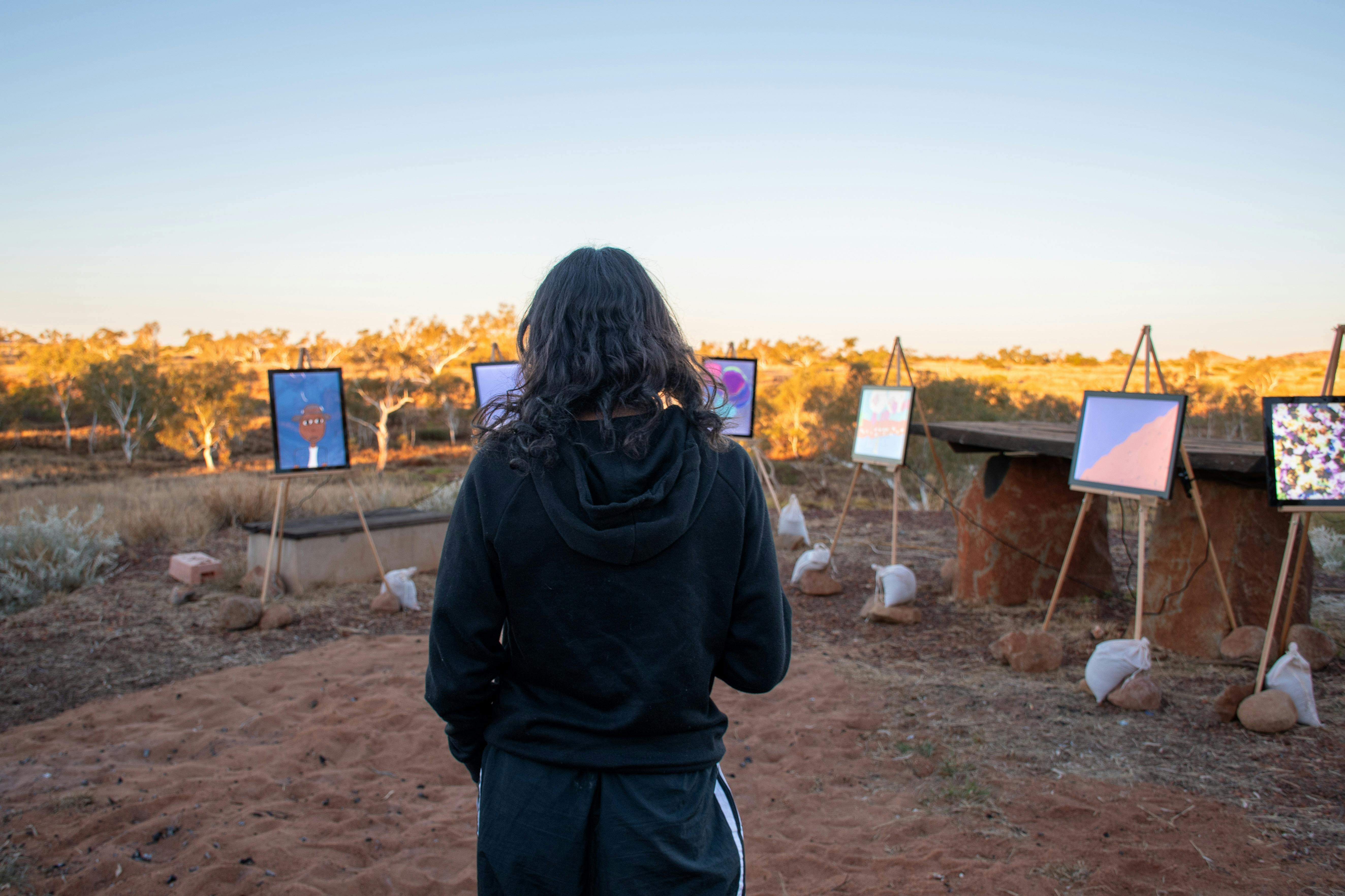 woman standing viewing digital art in lightboxes outside in Australian landscape