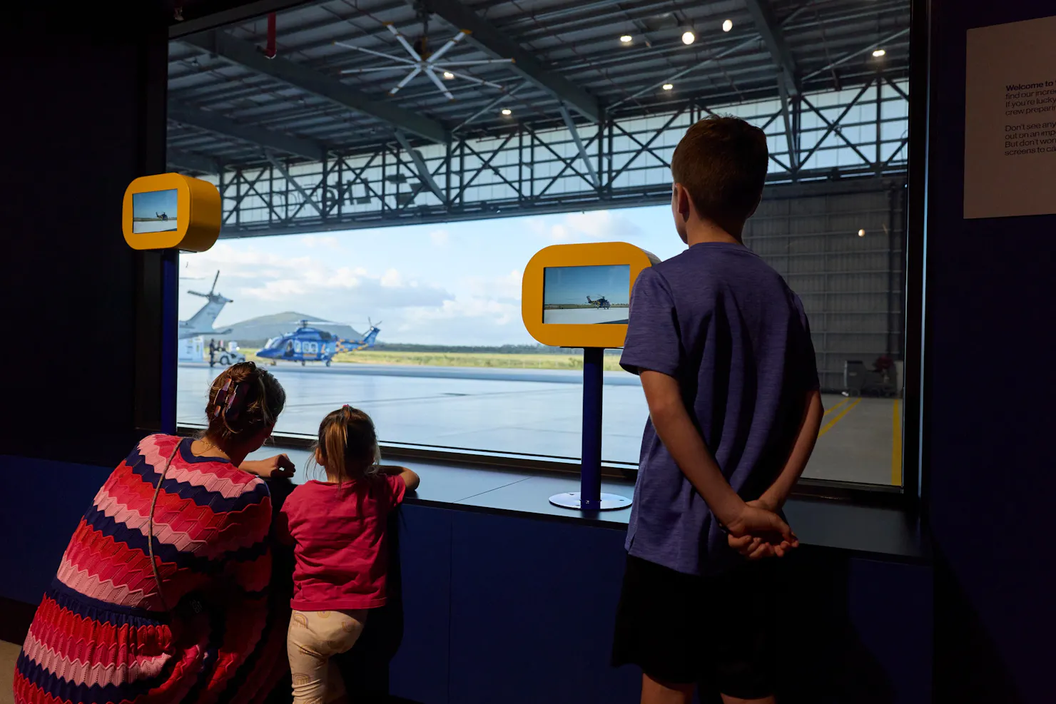 Family and kids looking at helicopter through viewing window at visitor centre