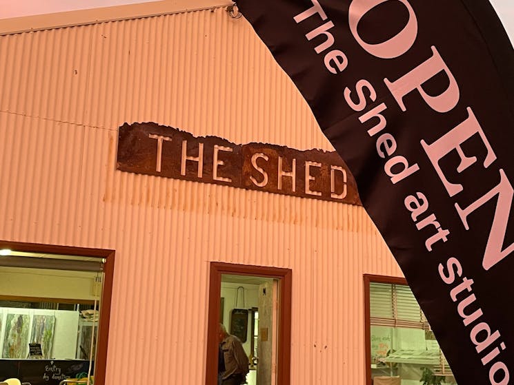 Facade of The Shed in evening light with flag in front advertising the art gallery open
