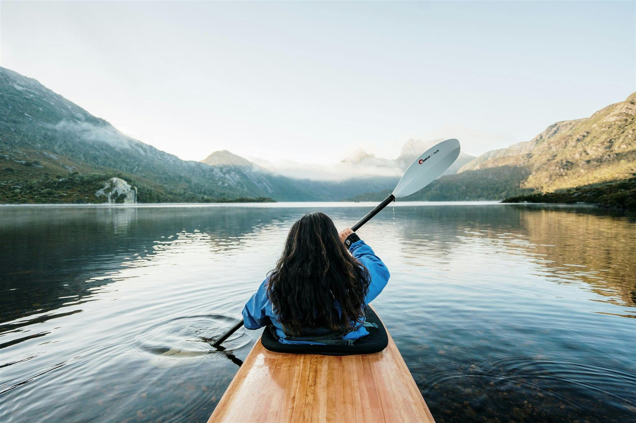 A woman sitting in the front of a timber kayak on Dove Lake
