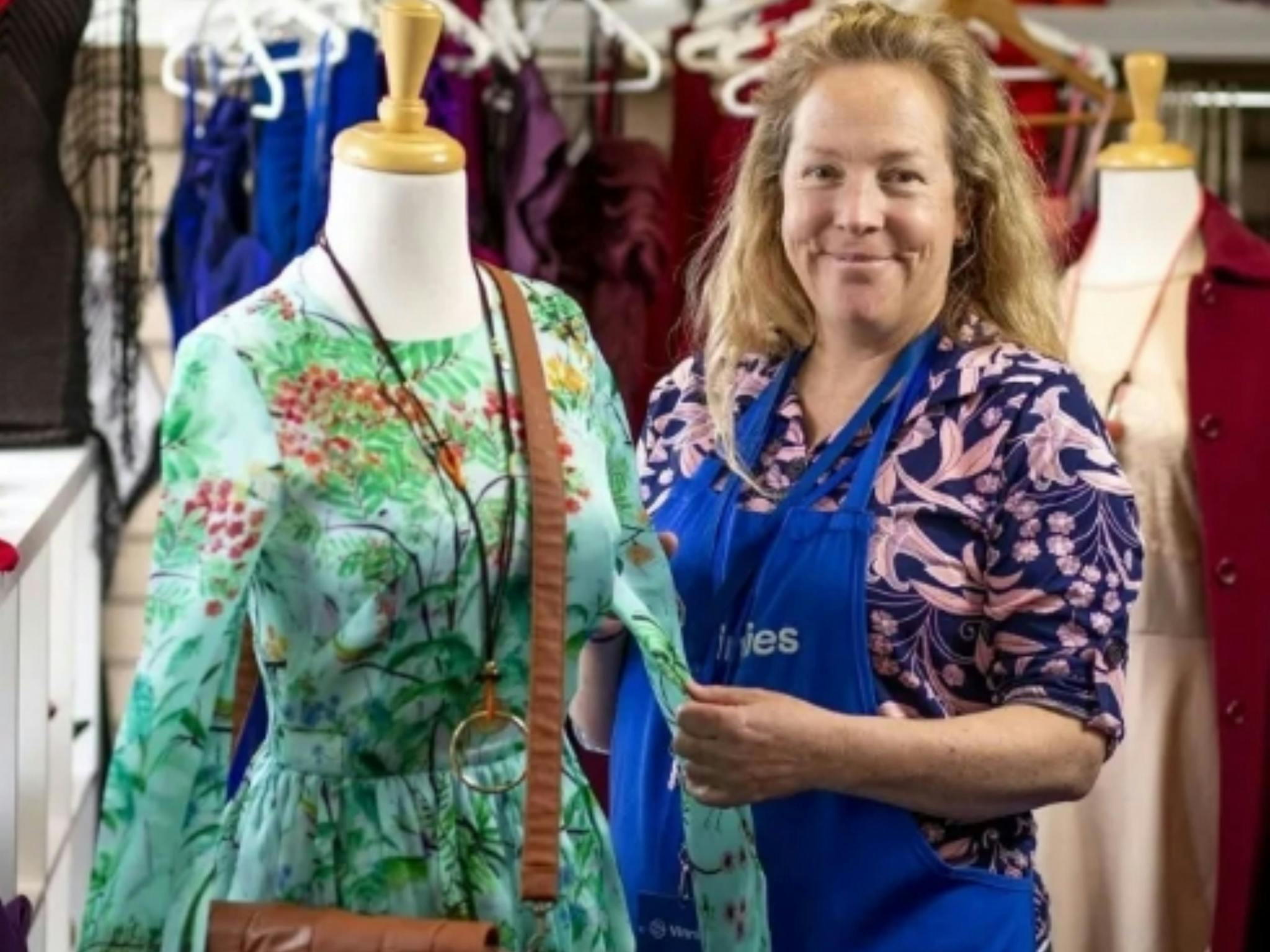 Image of a Vinnies volunteer putting a dress on a mannequin