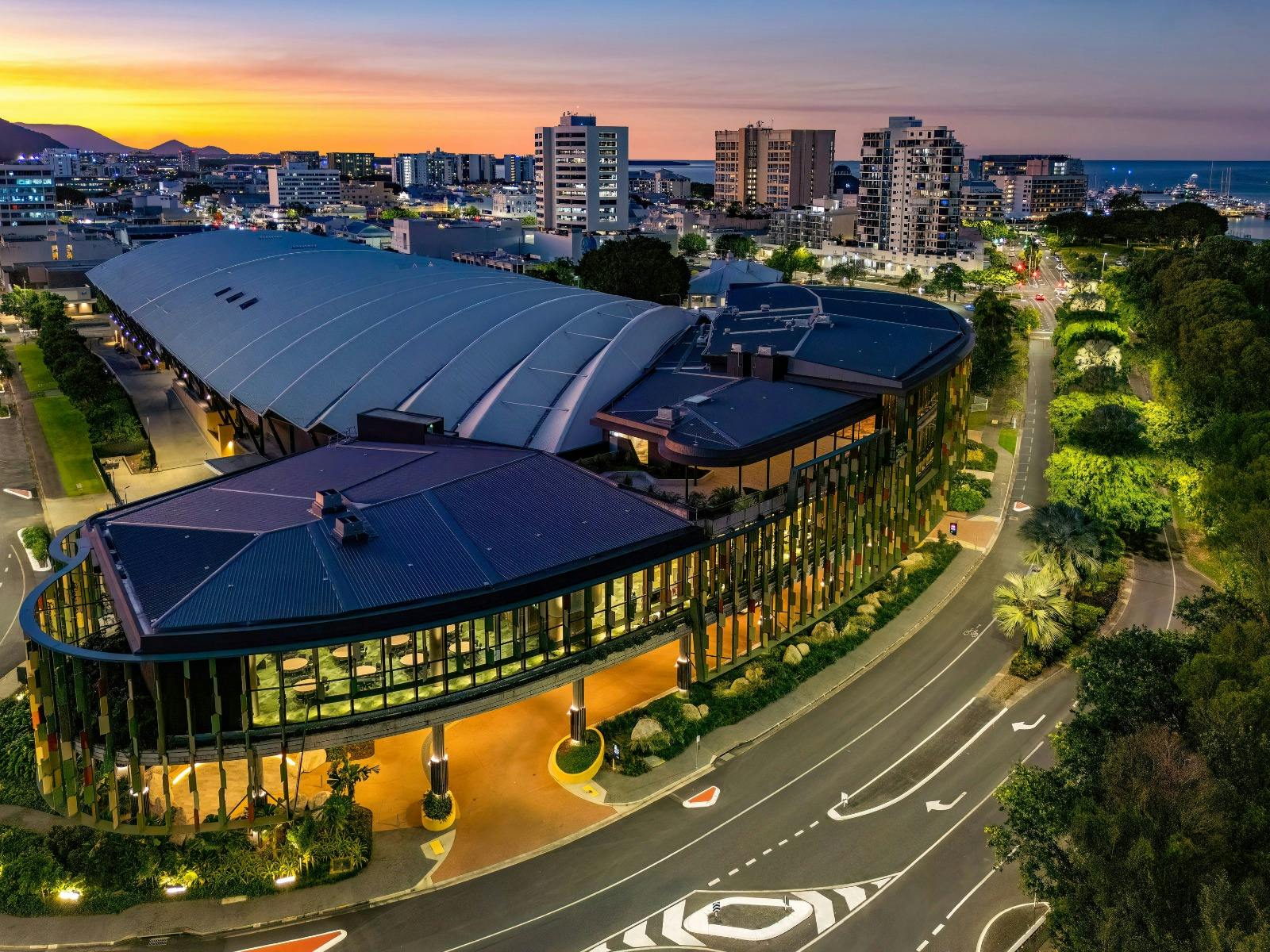 Aerial view of the Cairns Convention Centre at dusk, showcasing its modern architecture with a large