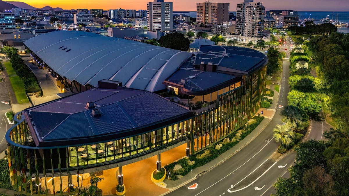 Aerial view of the Cairns Convention Centre at dusk, showcasing its modern architecture with a large