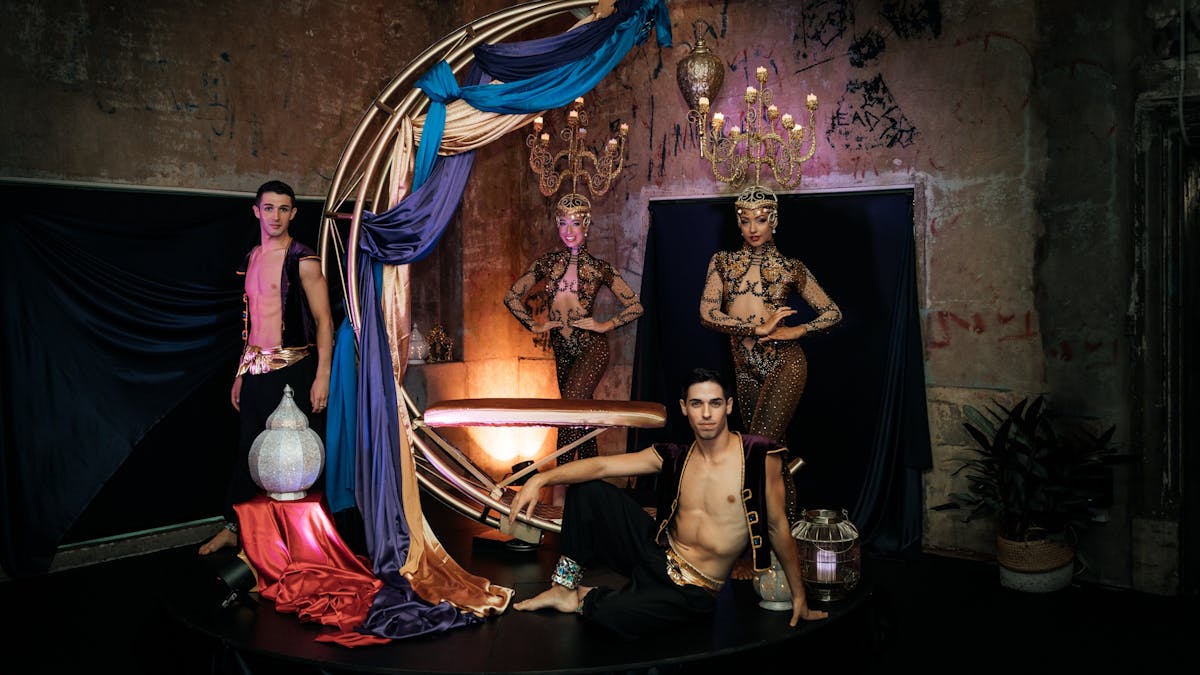 A giant gold moon has 2 male and 2 female performers posed around in Arabian costumes