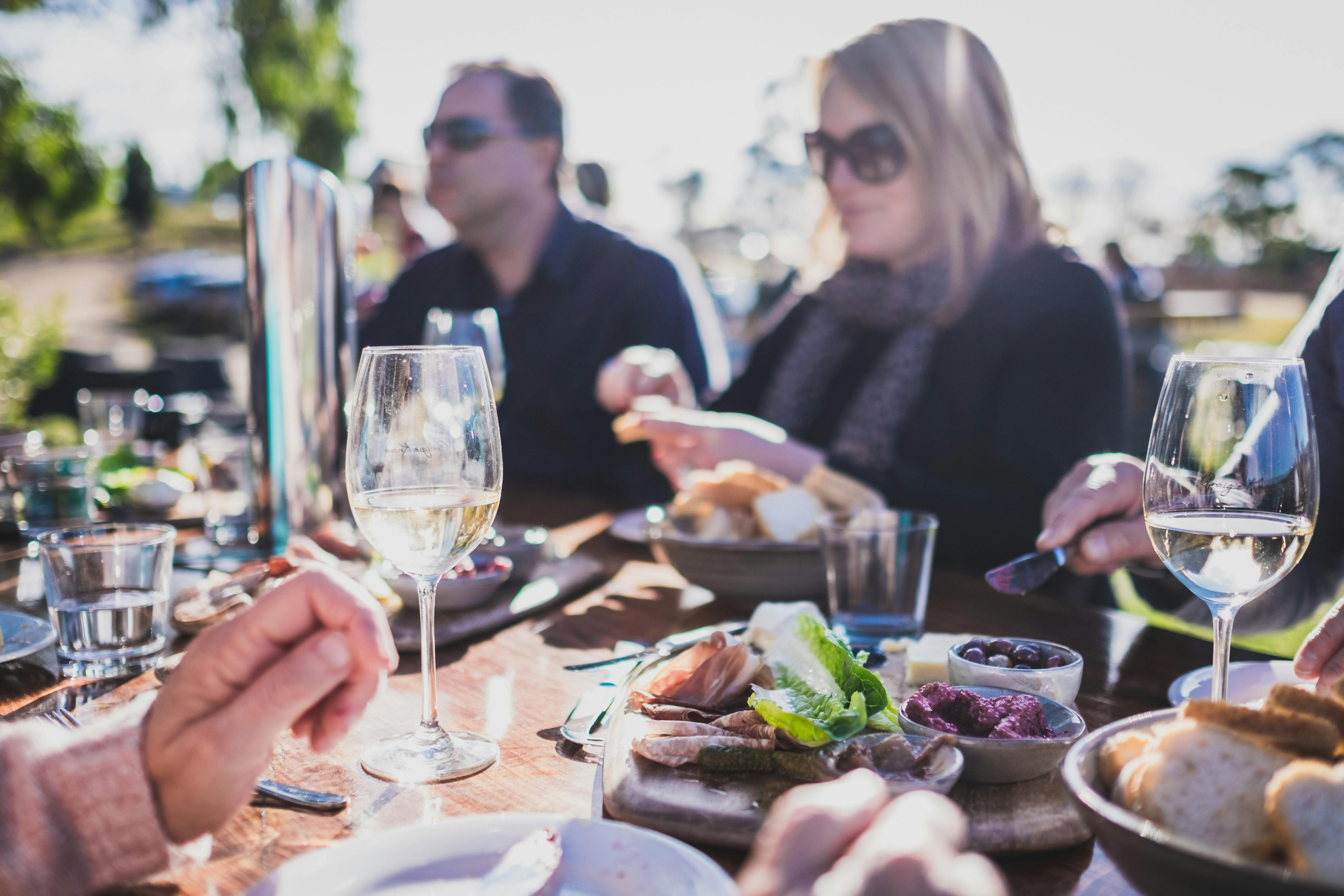 A group of people enjoying lunch and wine, outdoors at Craigie Knowe Vineyard